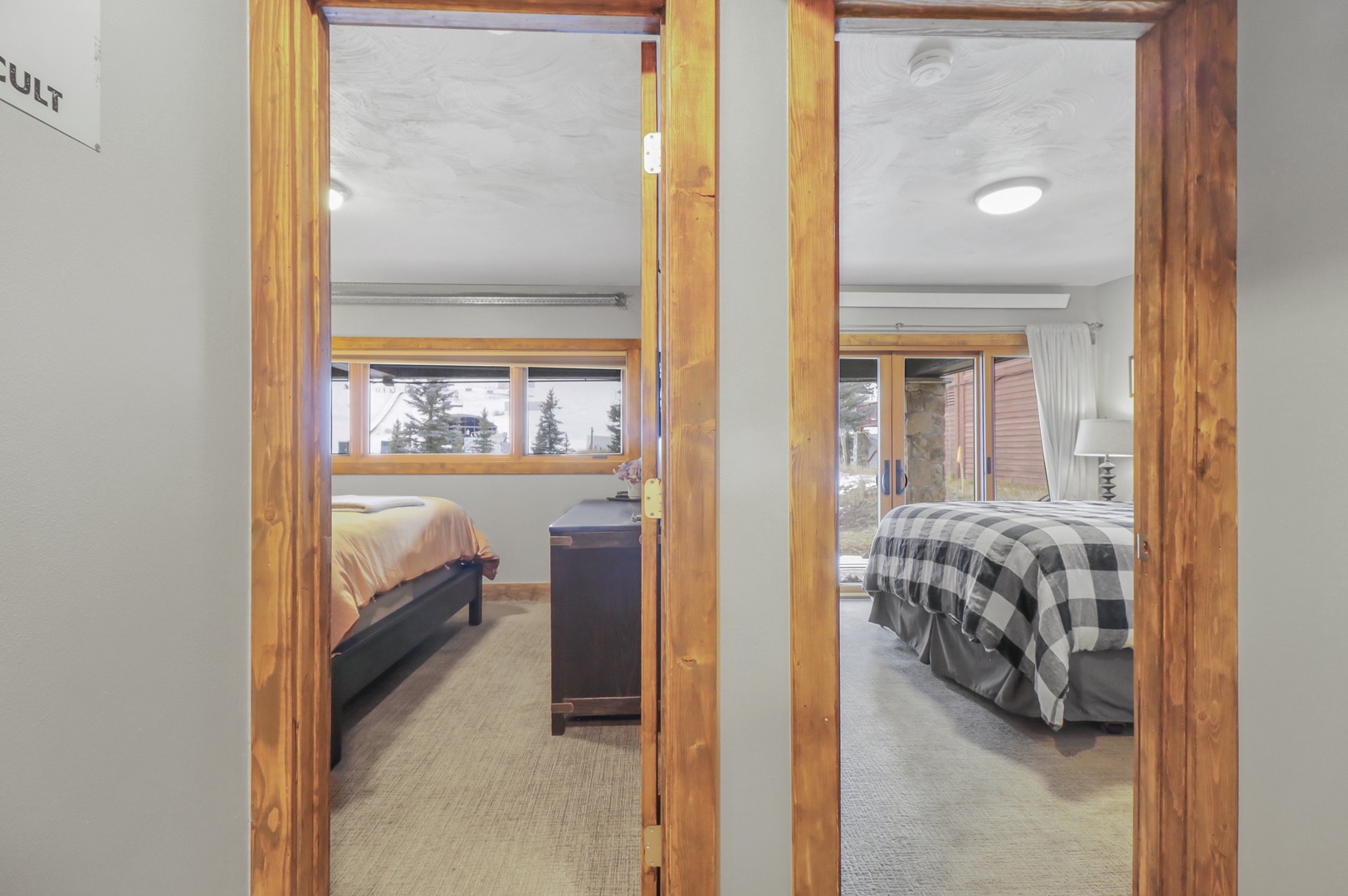 Step into your cozy retreat where warm wood accents frame two inviting bedrooms, each offering peaceful mountain views and comfortable beds for your perfect getaway.