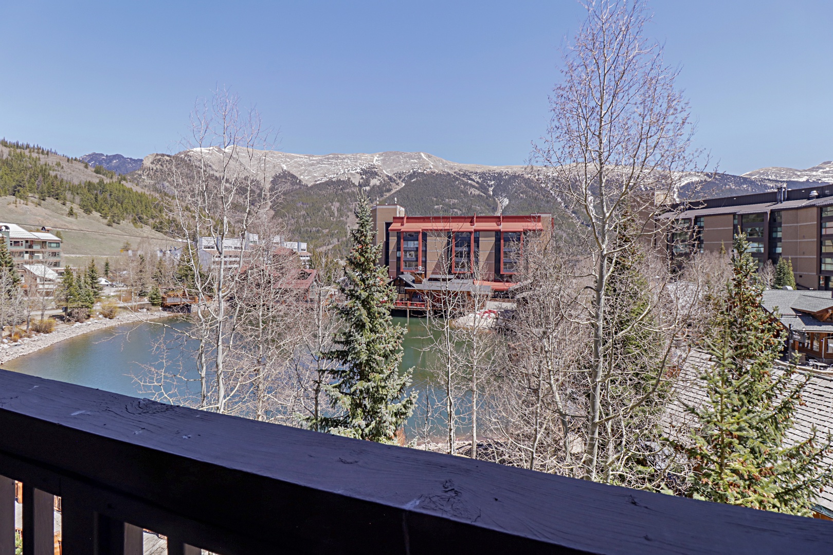 Mountain resort town view with snow-capped peaks, alpine lake, and surrounding buildings creating a picturesque ski destination backdrop.