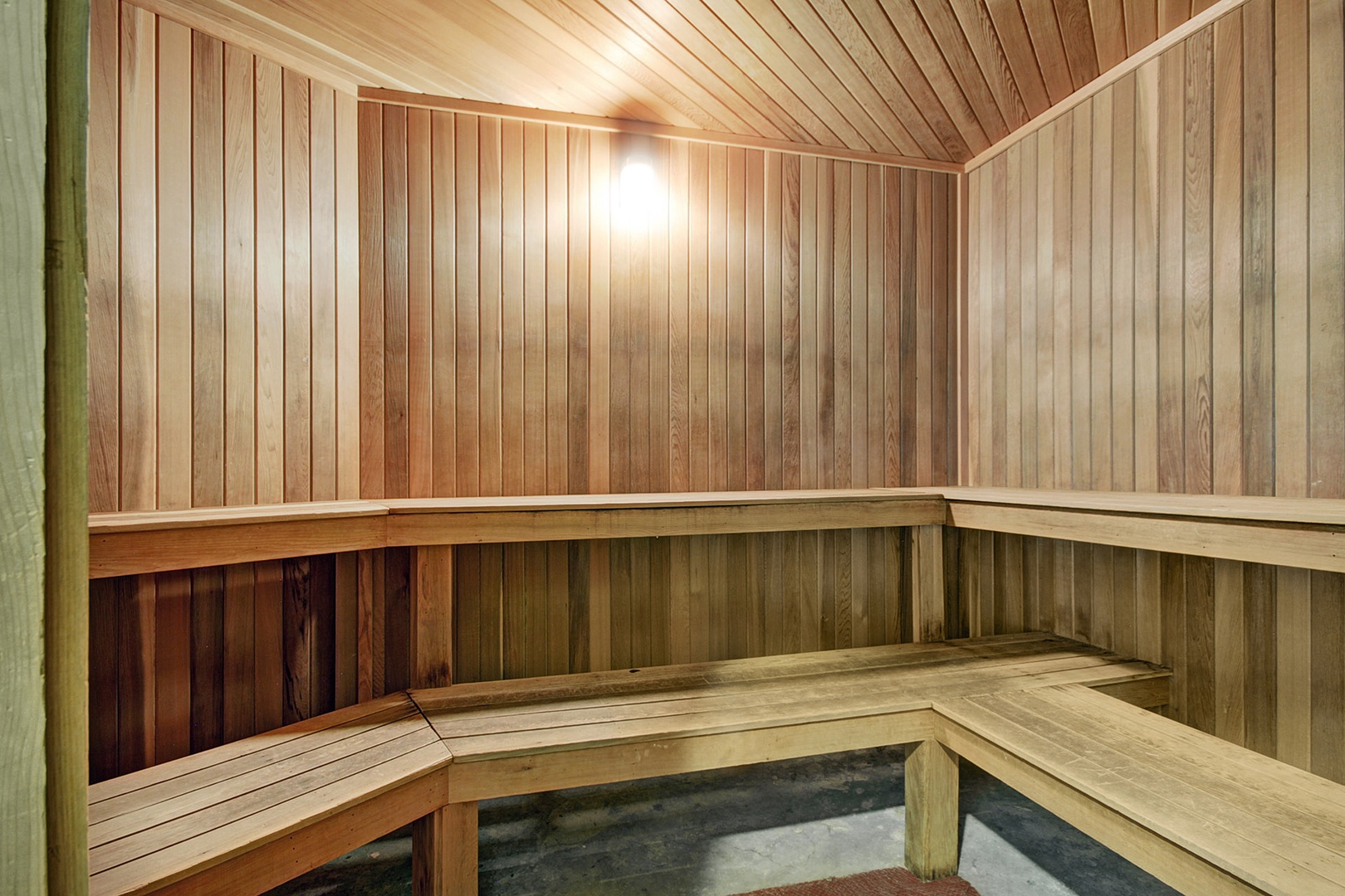 Step into the soothing warmth of the cedar-lined sauna, where natural wood tones and tiered benches invite you to unwind completely.