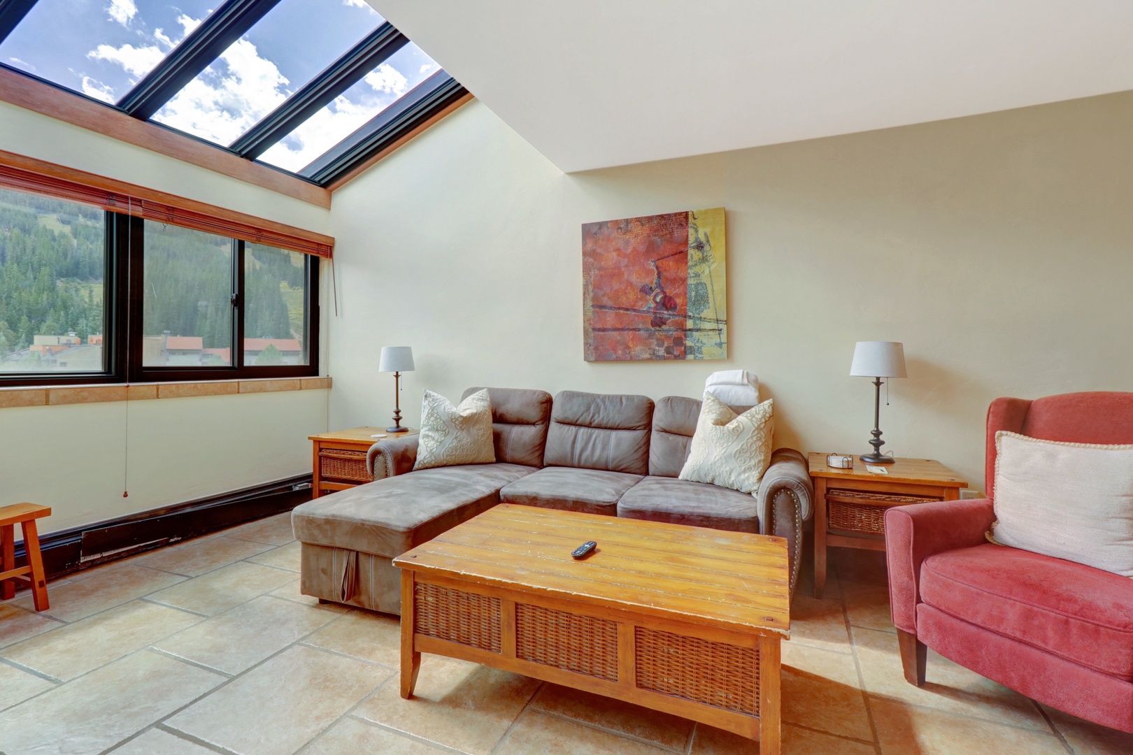 Comfortable living area featuring a plush sectional sofa and bright skylight windows that frame stunning mountain scenery. A relaxing space to unwind after a day of alpine adventure.