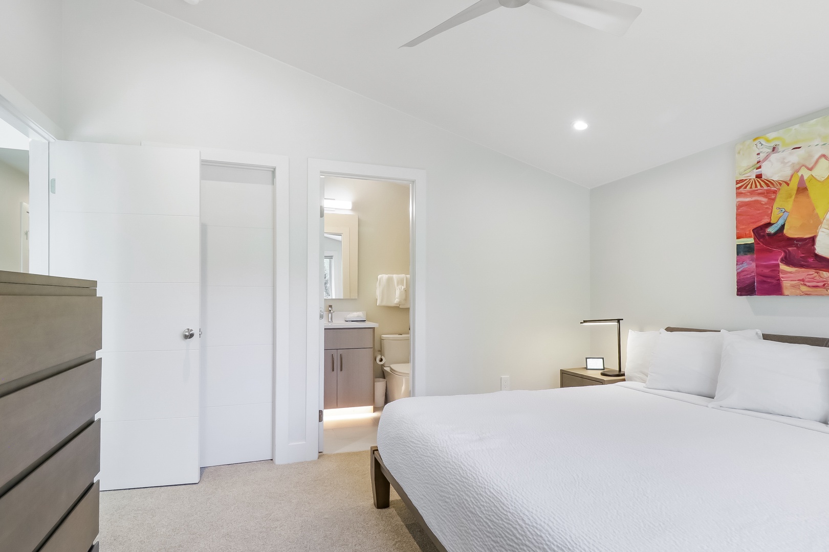 A bright, tranquil retreat with a plush bed and thoughtful touches. Notice the airy ceiling fan, soft lighting, and your private ensuite bathroom just steps away—everything designed for your comfort.