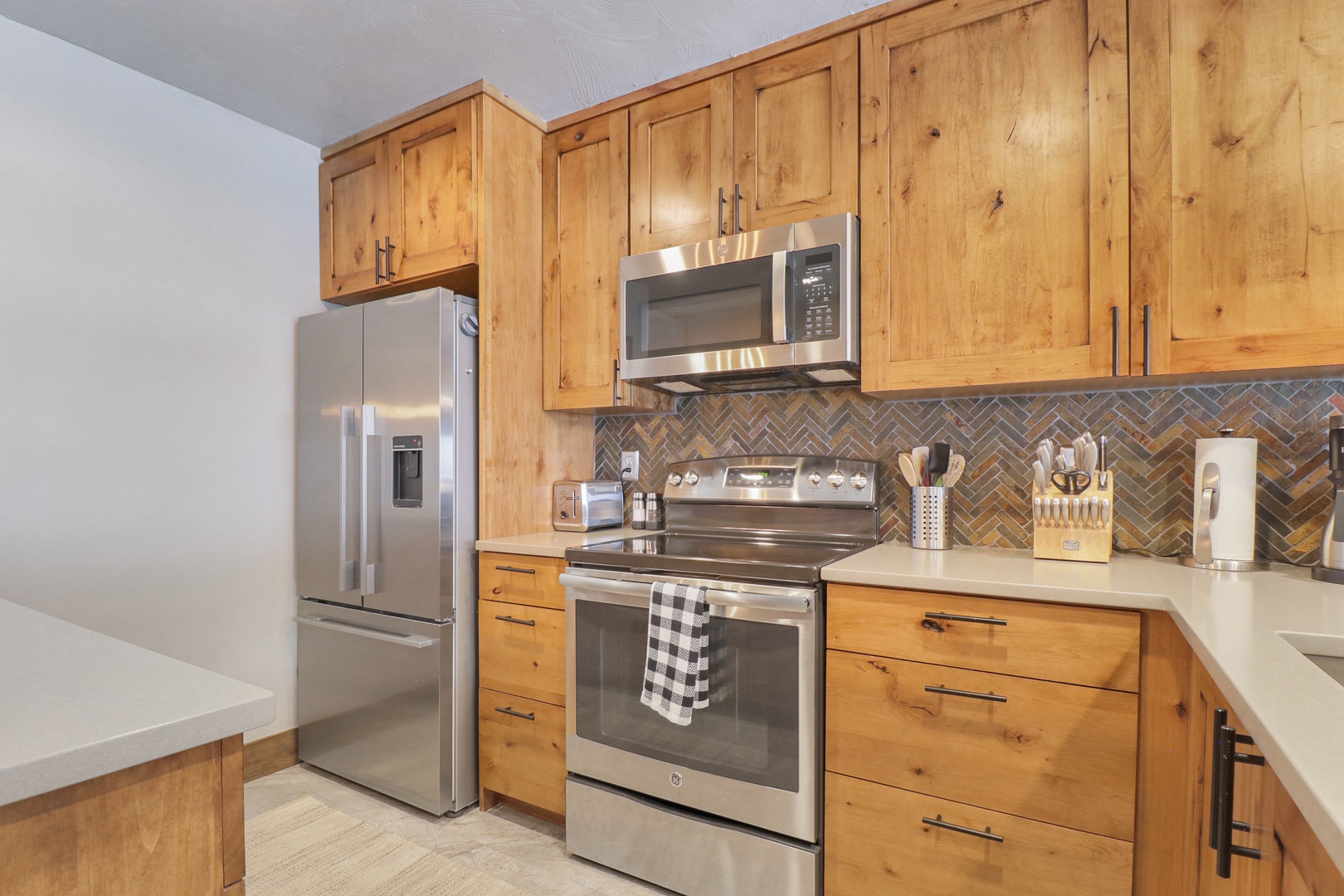 Step into your beautifully appointed kitchen where rustic charm meets modern convenience. Warm wood cabinetry and elegant tile backsplash create the perfect backdrop for preparing memorable meals during your stay.