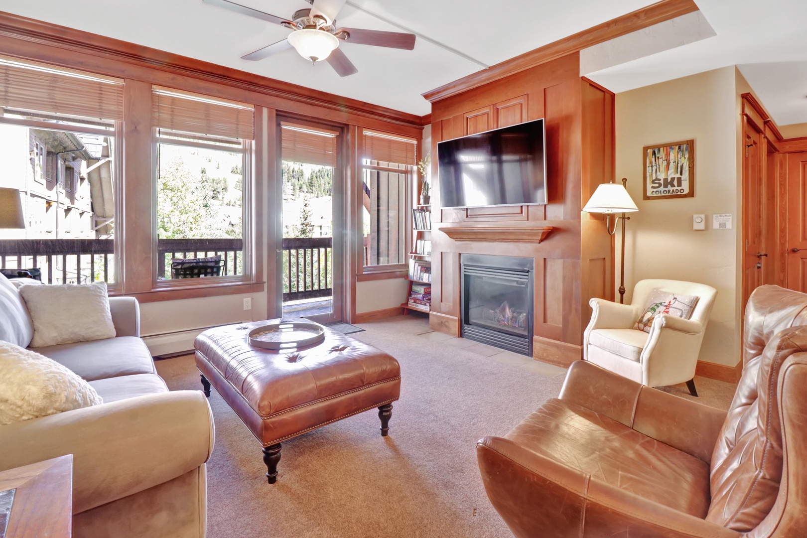 Settle into this warm mountain retreat where rich wood tones, plush seating, and a cozy fireplace invite you to unwind after your alpine adventures. Large windows frame serene views while you enjoy the spacious comfort of your living area.