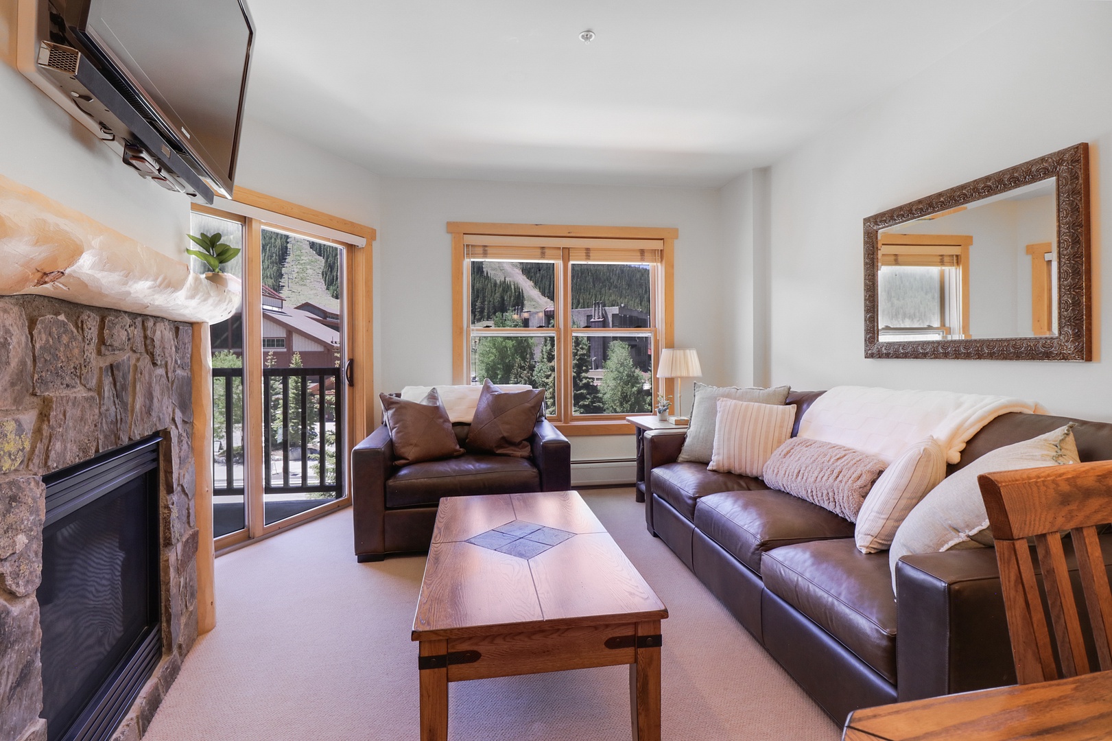 Sink into plush leather sofas by the stone fireplace, where mountain views frame your alpine getaway. Warm wood accents and cozy throws invite you to relax after a day exploring.