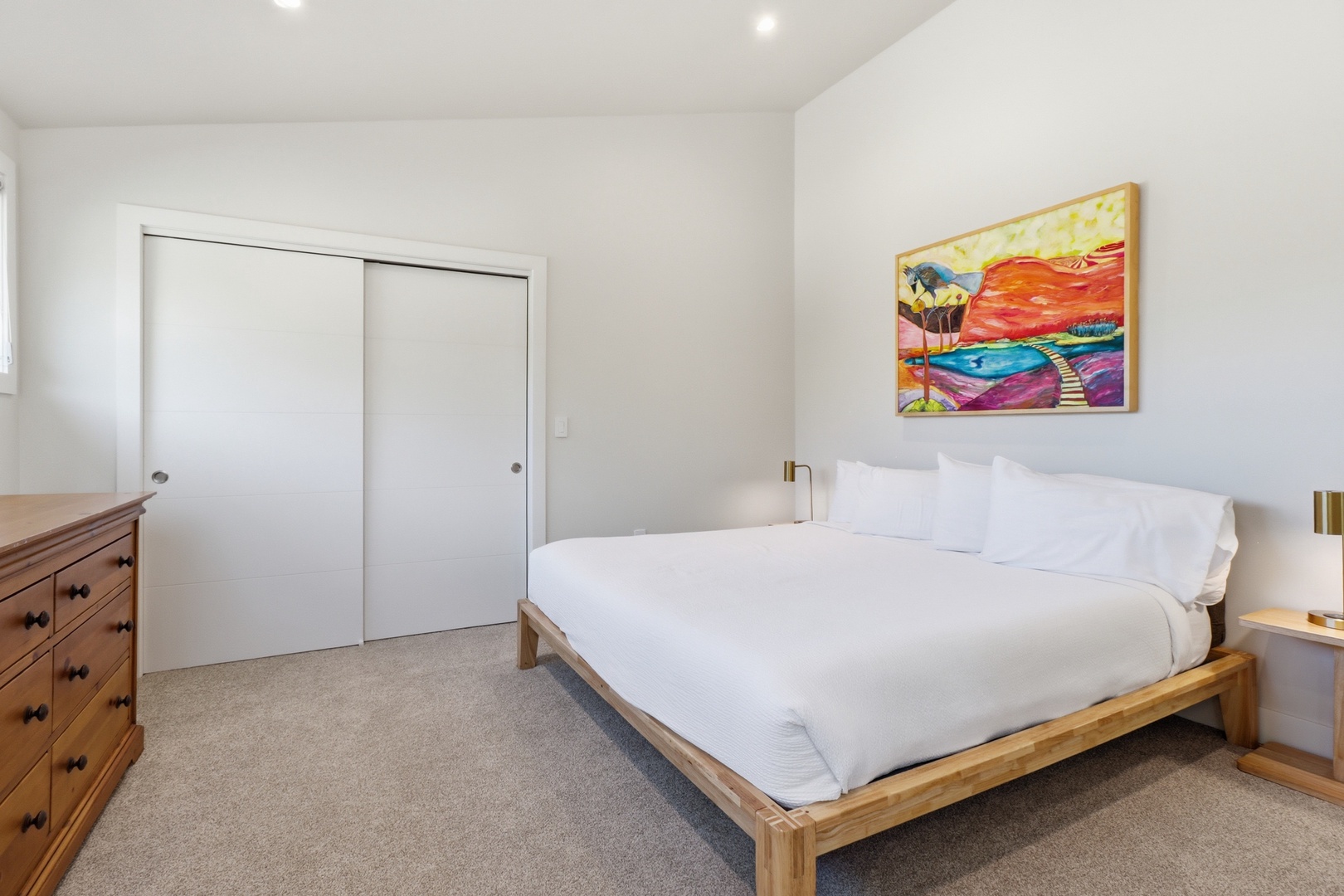 Unwind in your peaceful bedroom with a plush bed, soft linens, and vibrant coastal artwork that invites relaxation after a day of adventure.