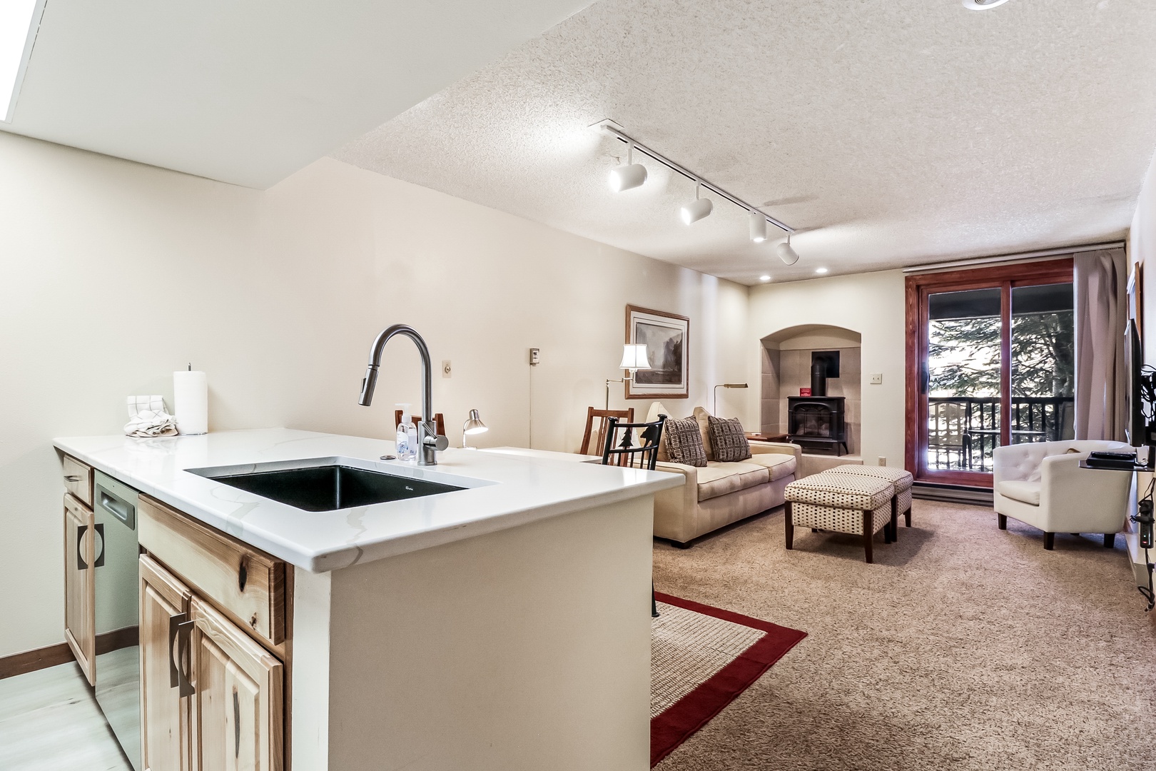 Step into your elegant open-concept space where the modern kitchen flows into a cozy living room with fireplace and mountain views.
