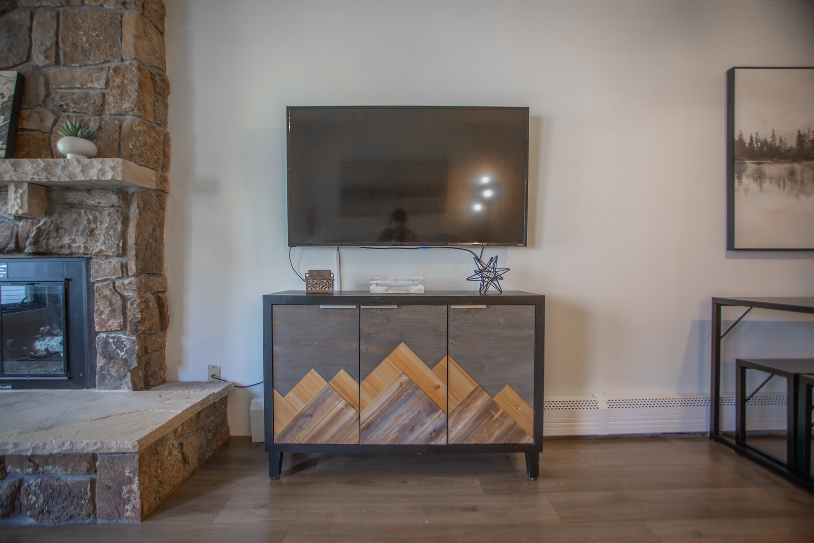Gather around your warm stone fireplace and cozy media console, perfectly framed by mountain-inspired woodwork and thoughtful decor touches.