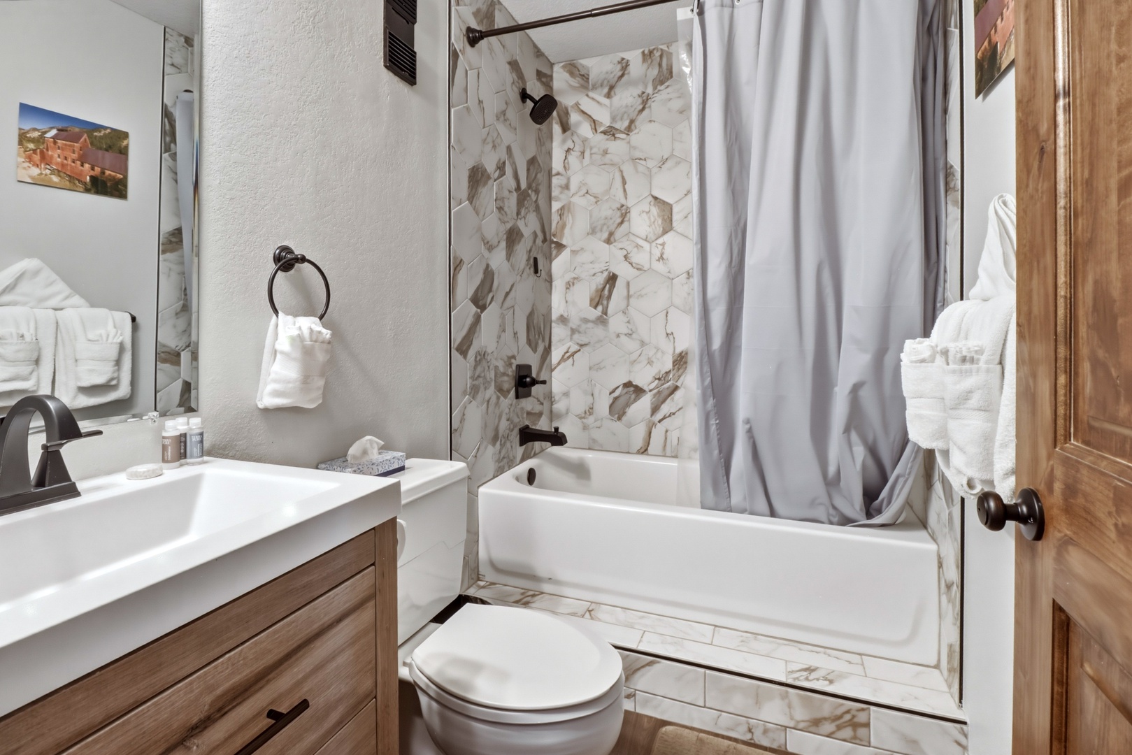 Your private bathroom features elegant marble-look tile and warm wood accents, creating a spa-like retreat for your stay.