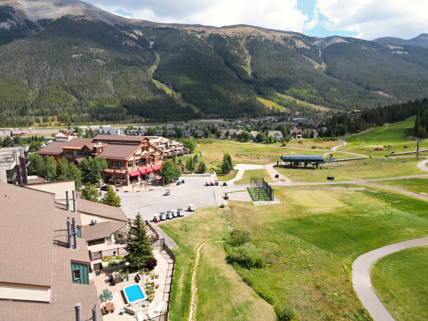 Mountain resort community nestled in a dramatic valley with ski slopes, golf course, and residential developments below forested peaks.