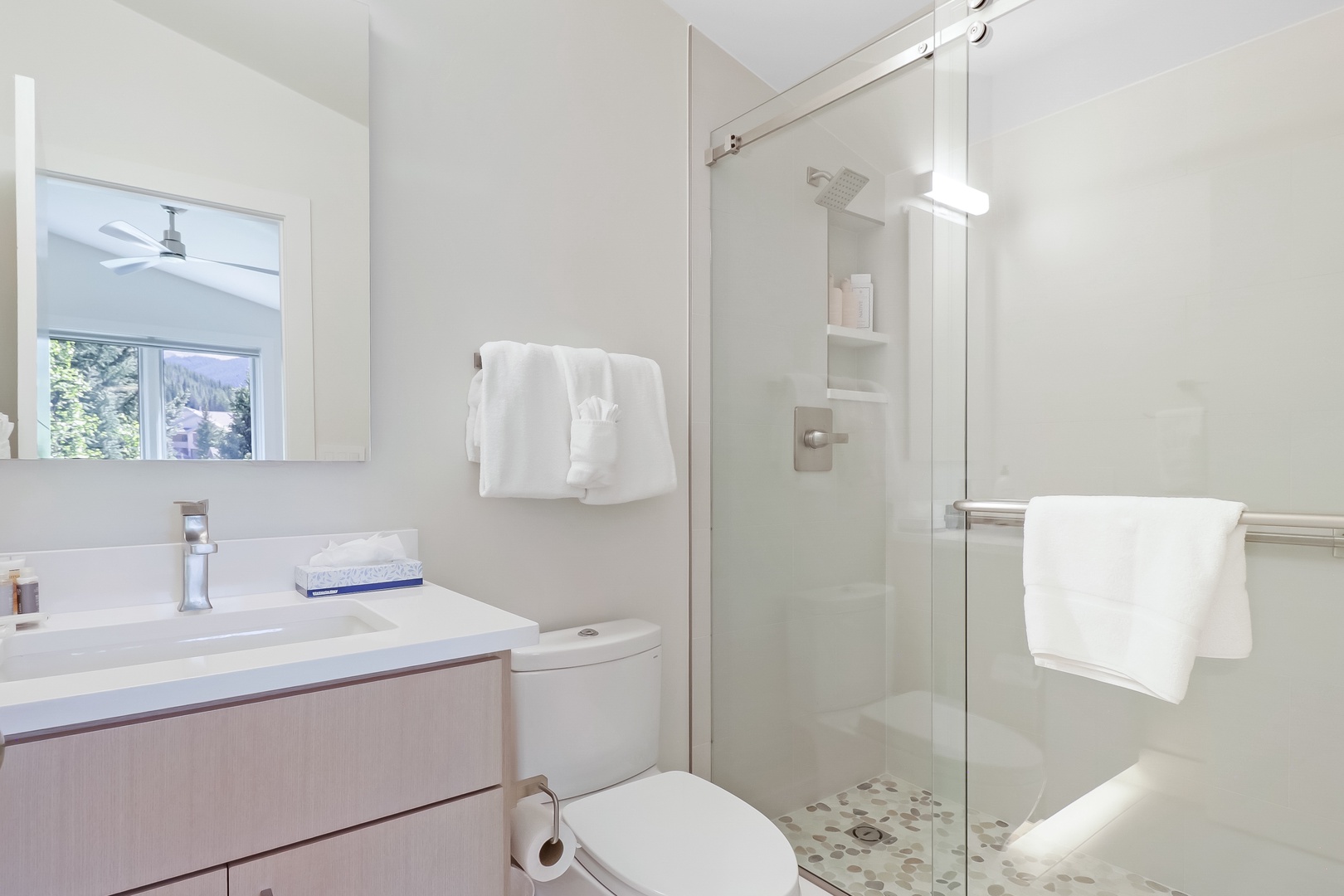 Enjoy your private bathroom featuring a sleek glass-enclosed shower, modern vanity, and fresh towels waiting just for you.