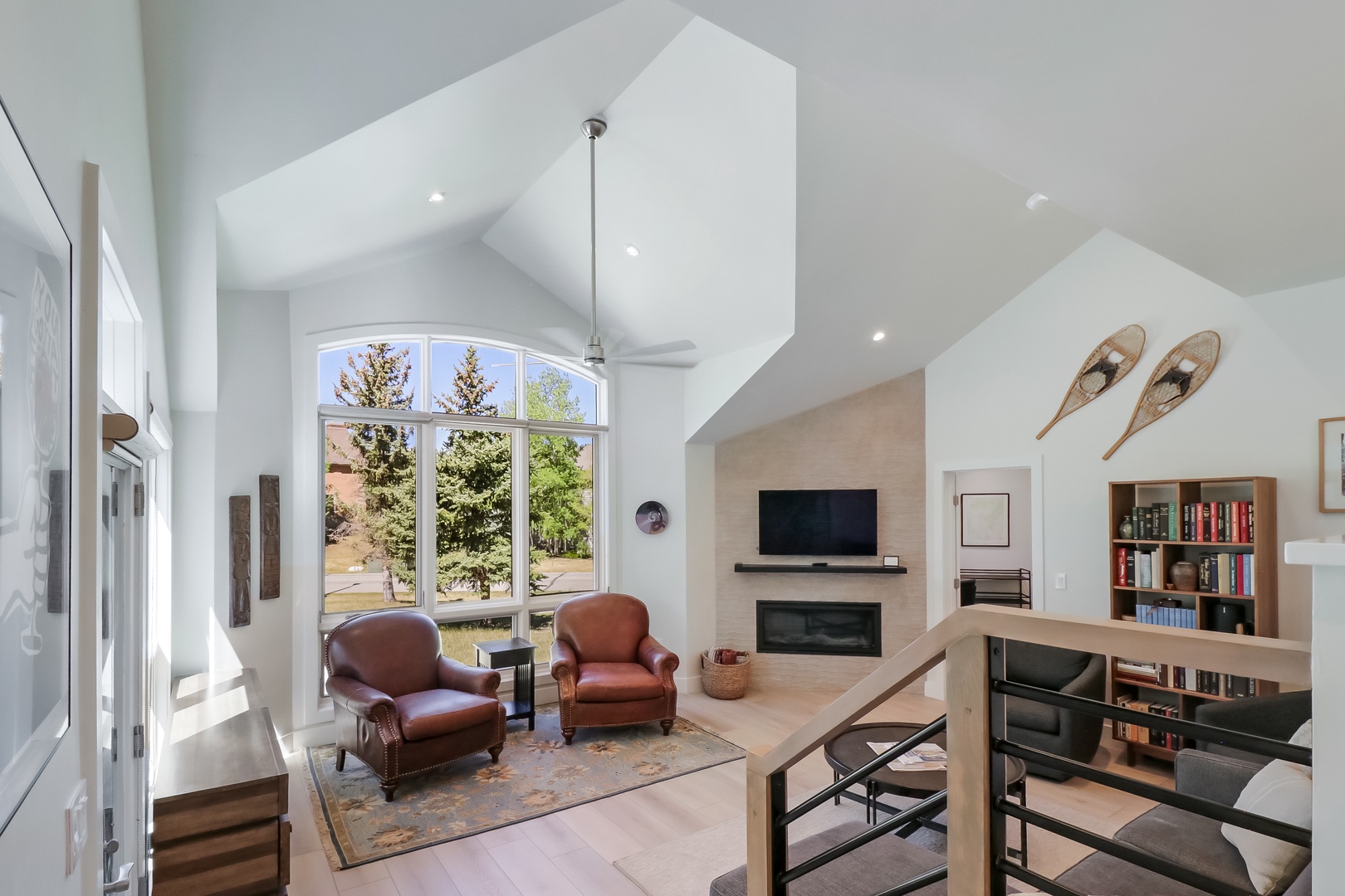 Relax in your airy living room, where soaring ceilings and sun-filled windows frame stunning views, a cozy fireplace awaits, and thoughtful décor invites you to unwind.