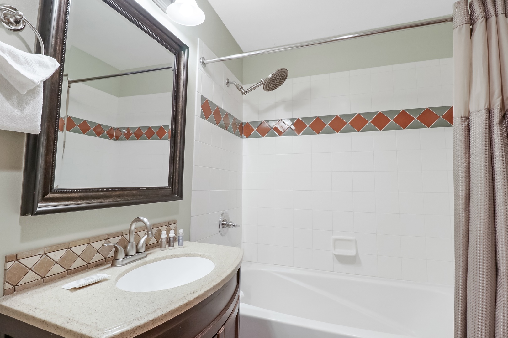 Freshen up in your private bathroom, featuring a tiled tub-shower combination with decorative accents and all the essentials for your stay.