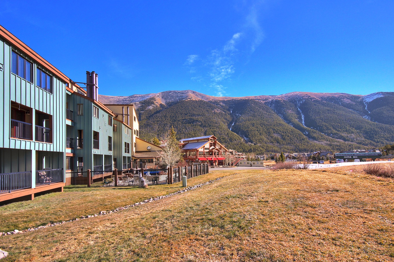 Modern mountain resort buildings nestled against dramatic ski slopes under brilliant blue skies in this scenic alpine destination.