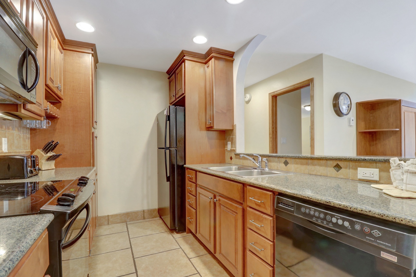 Bright and functional kitchen featuring granite countertops, warm wood cabinetry, and a convenient breakfast bar—perfect for casual meals or entertaining.