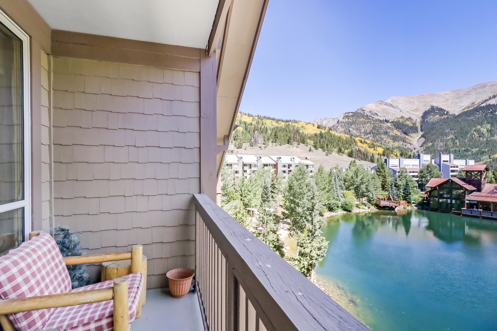 Settle into the cozy balcony chair and take in the serene alpine lake, evergreen trees, and dramatic mountain peaks that frame your private retreat.