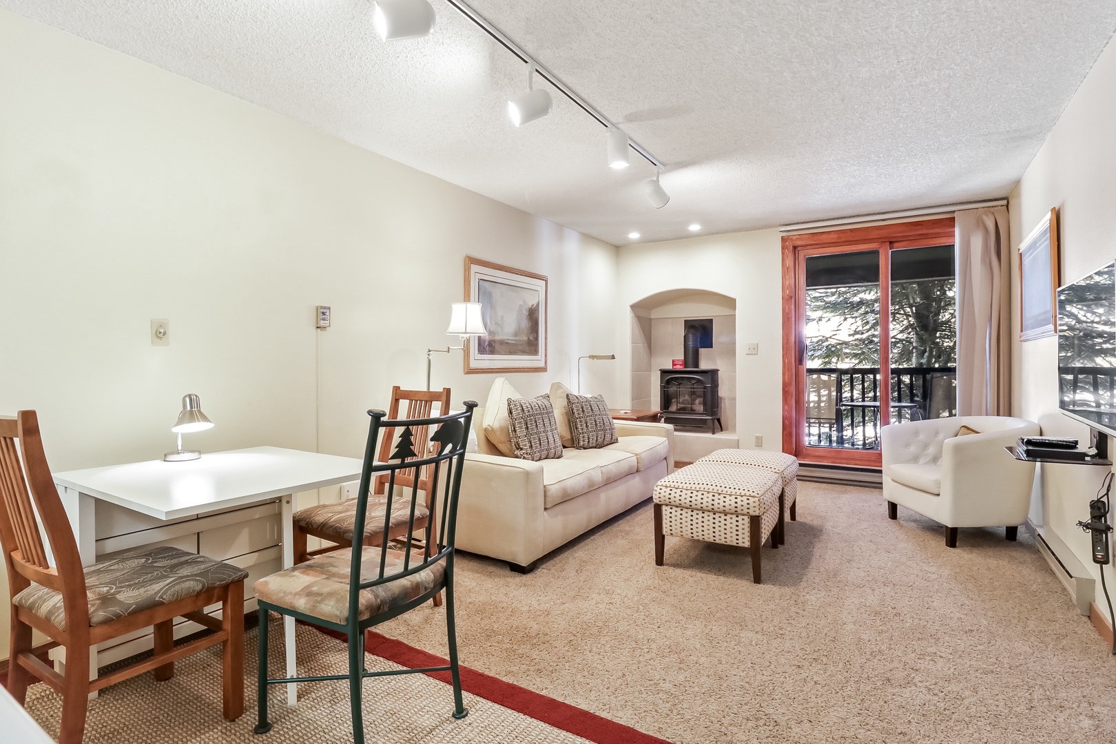 Relax in your bright living space with cozy seating, natural light streaming through French doors, and a warm fireplace for chilly evenings.