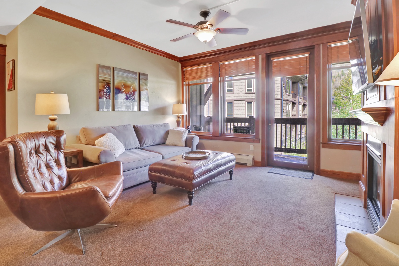 Settle into your inviting living space with plush seating, rich wood accents, and a private balcony where natural light pours in through floor-to-ceiling windows.