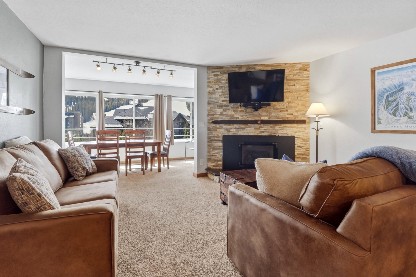 Cozy up by your stone fireplace while enjoying mountain views through expansive windows in this inviting living space.