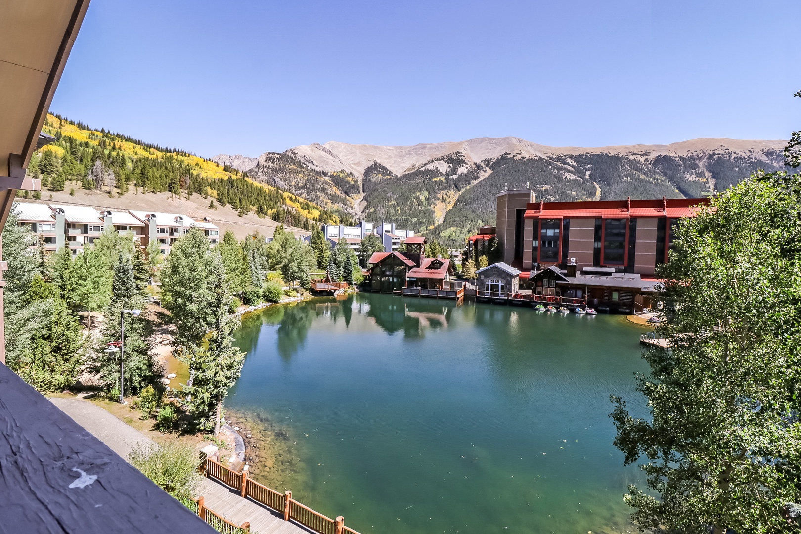 Mountain views framing a serene alpine lake, with colorful hillsides and surrounding lodges creating a peaceful retreat setting.