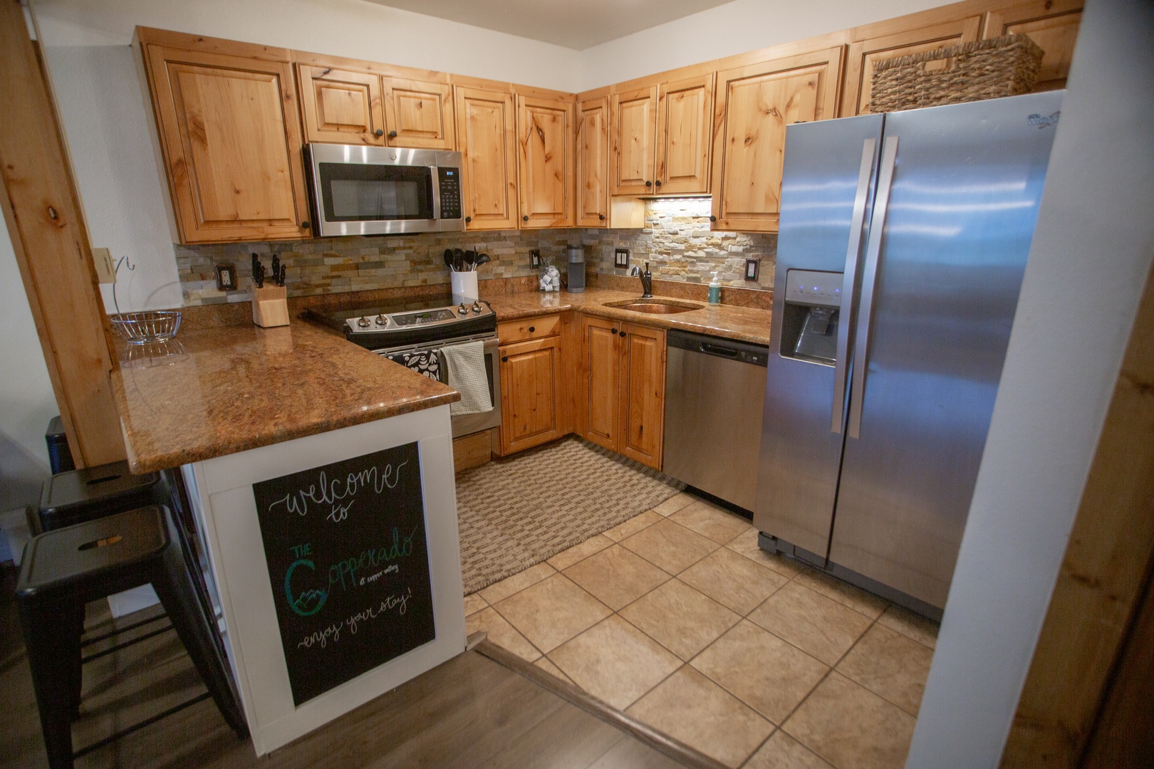 Your fully equipped kitchen features granite counters, stainless appliances, and warm wood cabinetry, inviting you to prepare delicious meals in a cozy mountain retreat setting.