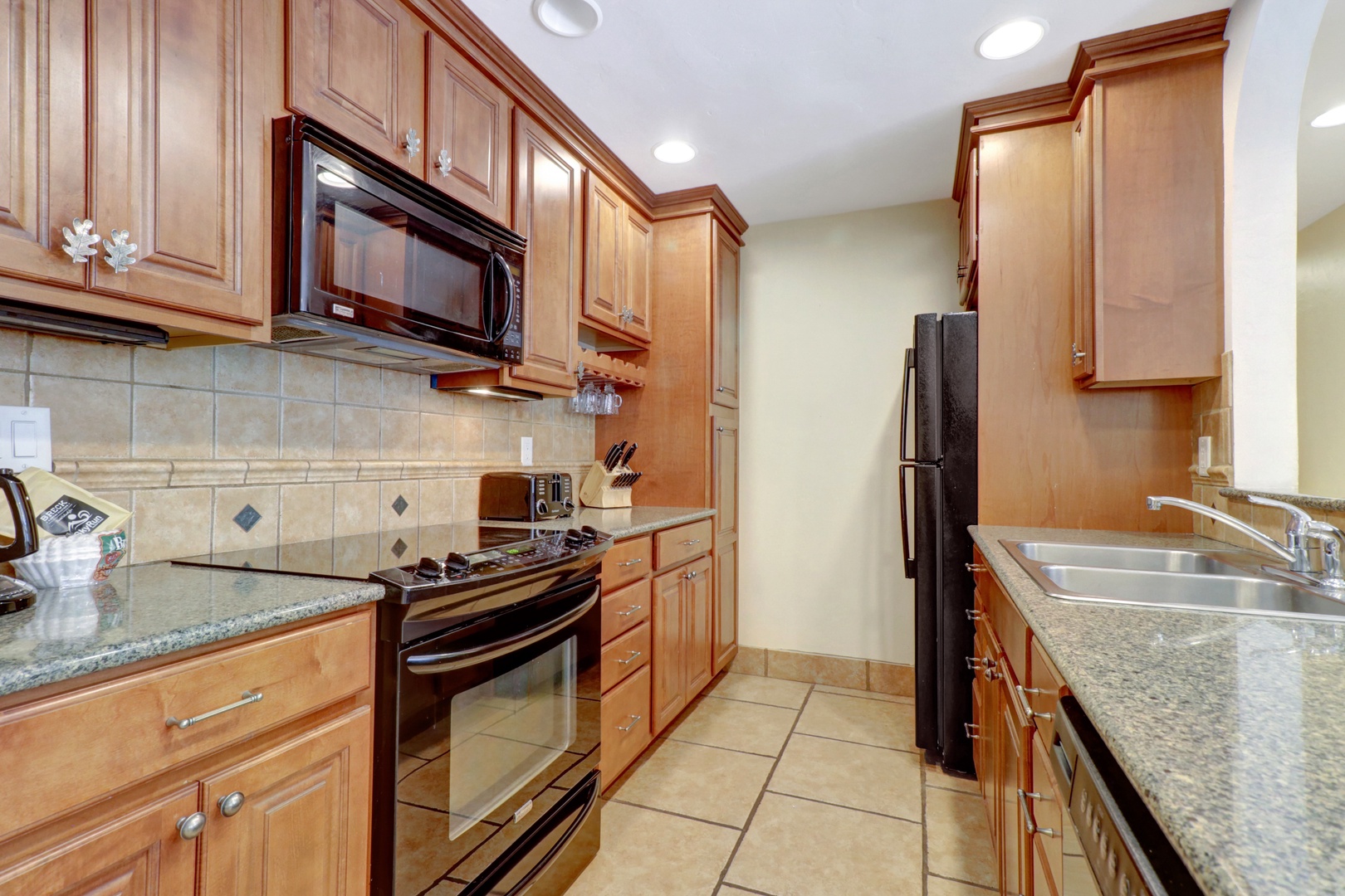 Bright and functional kitchen featuring granite countertops, warm wood cabinetry, and a convenient breakfast bar—perfect for casual meals or entertaining.