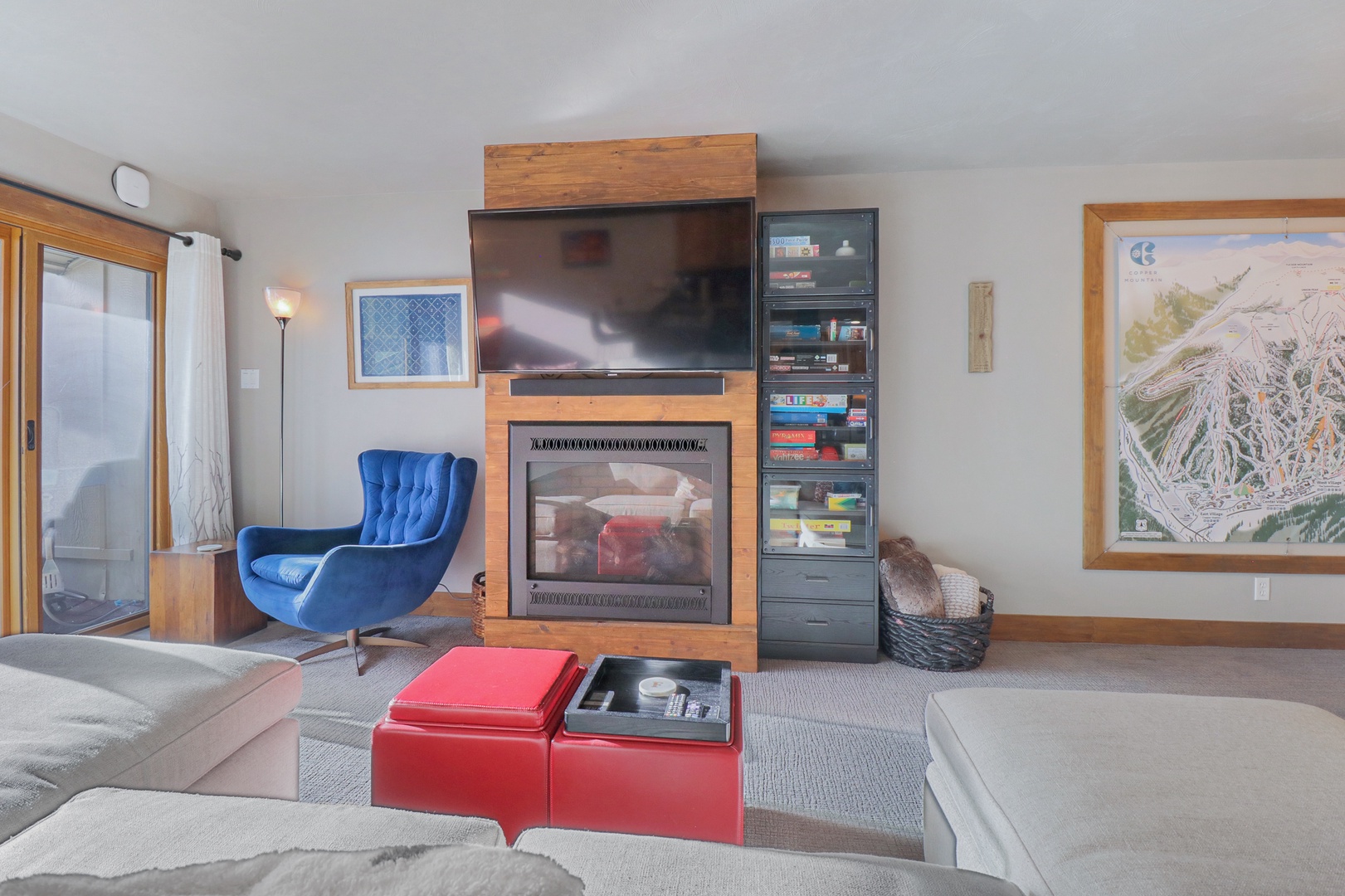 Settle into this inviting living space where you can curl up by the crackling fireplace while watching your favorite shows. The vibrant blue chair beckons for cozy reading sessions.