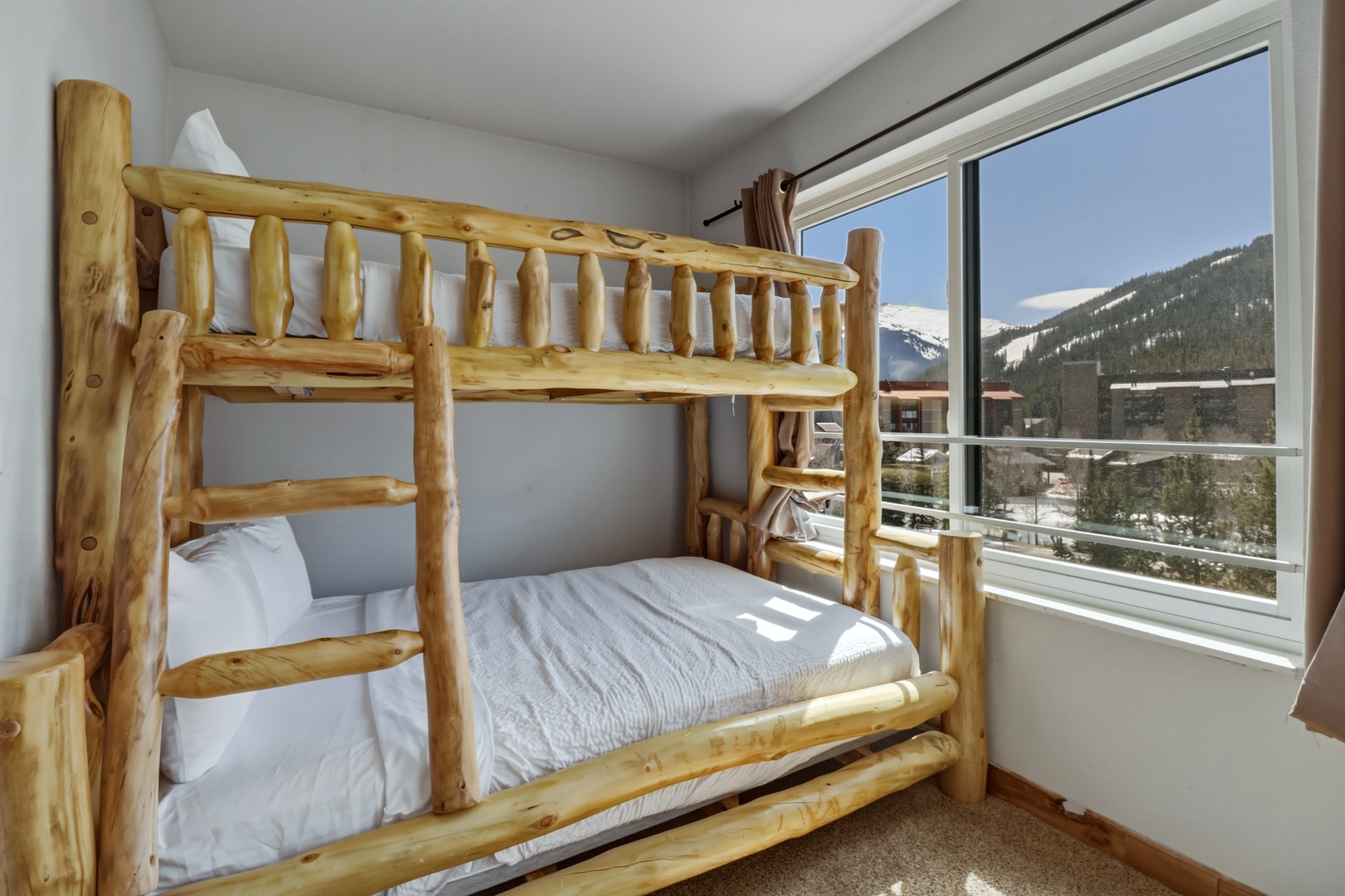 Your cozy mountain retreat features rustic log bunk beds with crisp linens, perfect for family adventures with stunning alpine views.