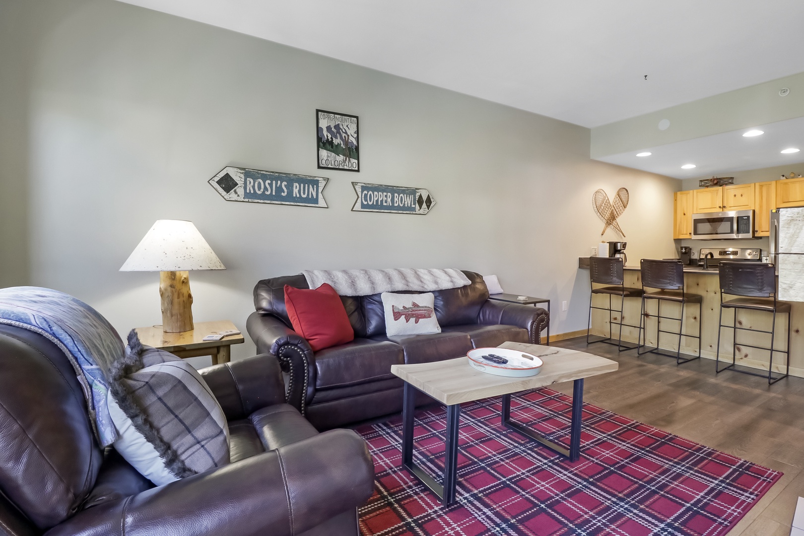 Sink into plush leather sofas in your Colorado-themed living space, where rustic mountain charm meets modern comfort with an open kitchen just steps away.
