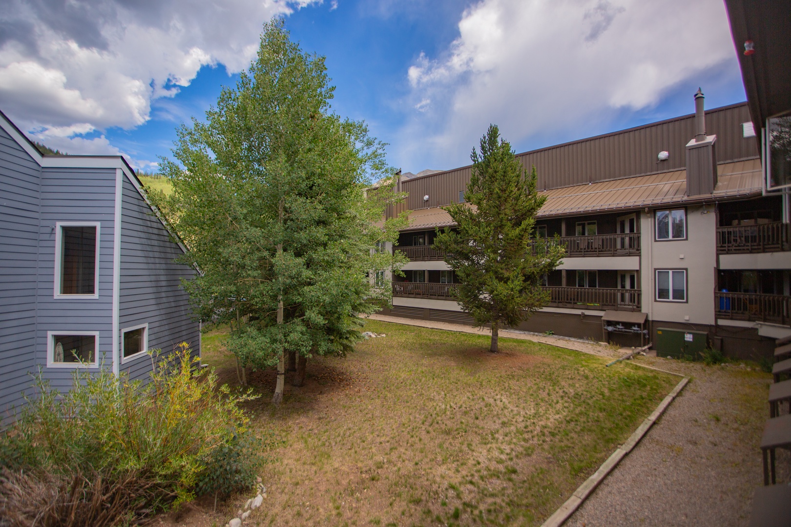 A multi-building vacation property complex surrounded by mature trees and natural mountain scenery, offering a peaceful retreat setting.