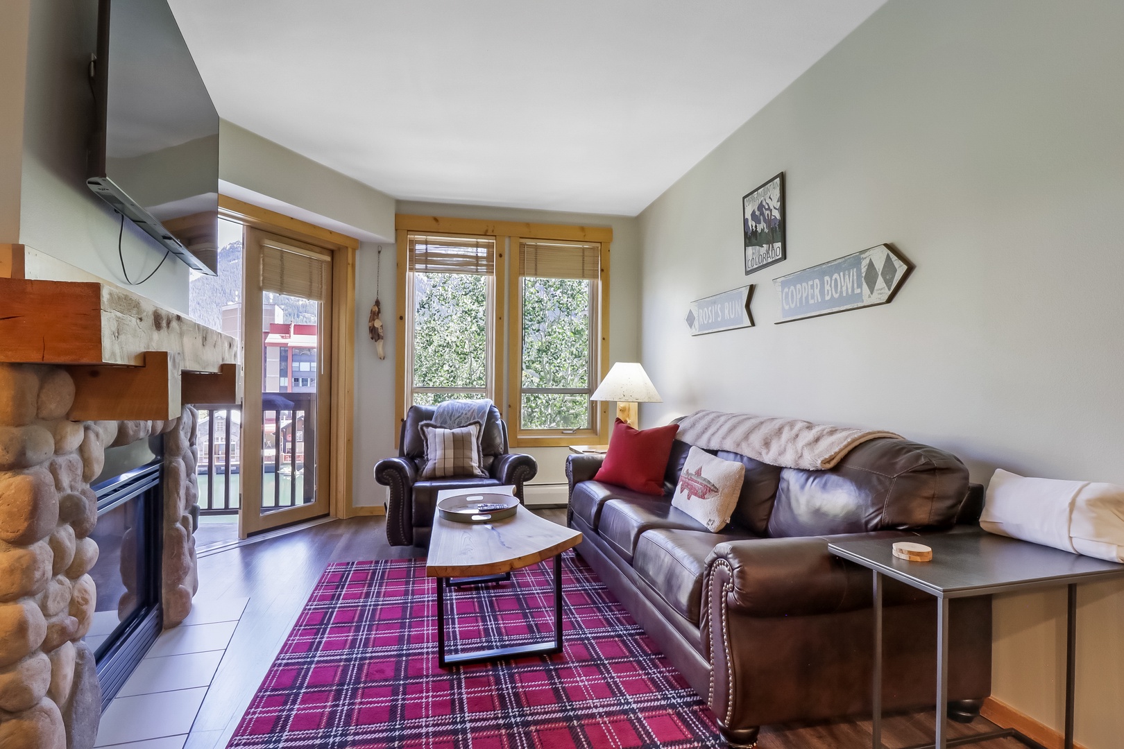 Settle into your cozy mountain retreat with plush leather seating, a warming fireplace, and balcony access where fresh alpine air awaits just beyond the doors.