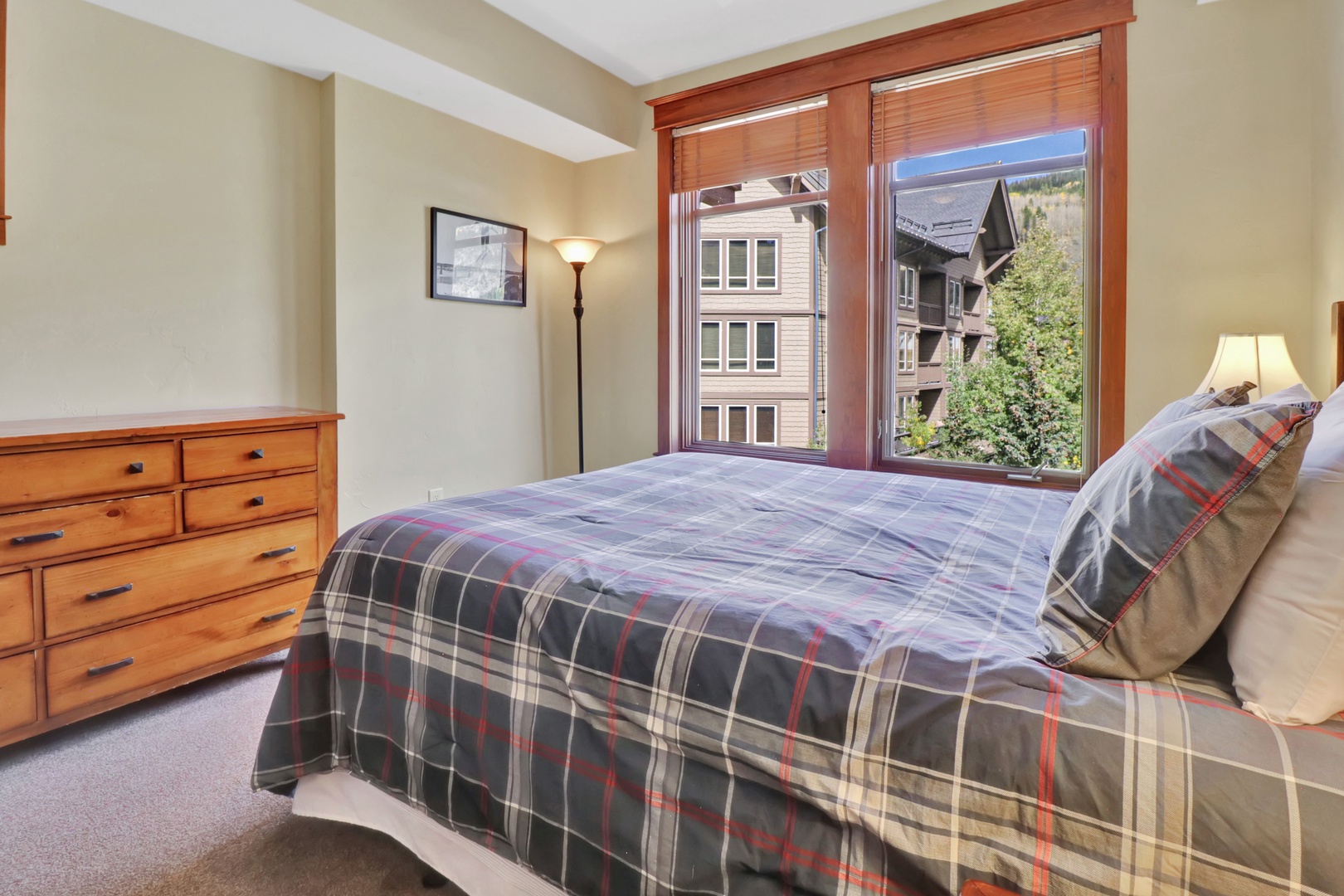 Unwind in your cozy bedroom where warm wood tones and soft plaid bedding create a welcoming mountain retreat. Step outside to your private balcony and breathe in the fresh alpine air.