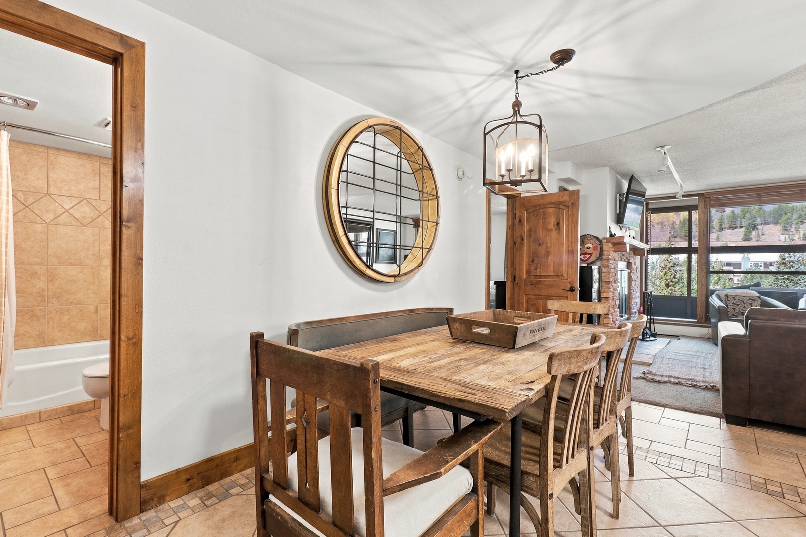 Gather around this rustic dining table where you can share stories over meals. The warm wood tones and open layout connect you to the cozy living space, creating a welcoming home-away-from-home feel.