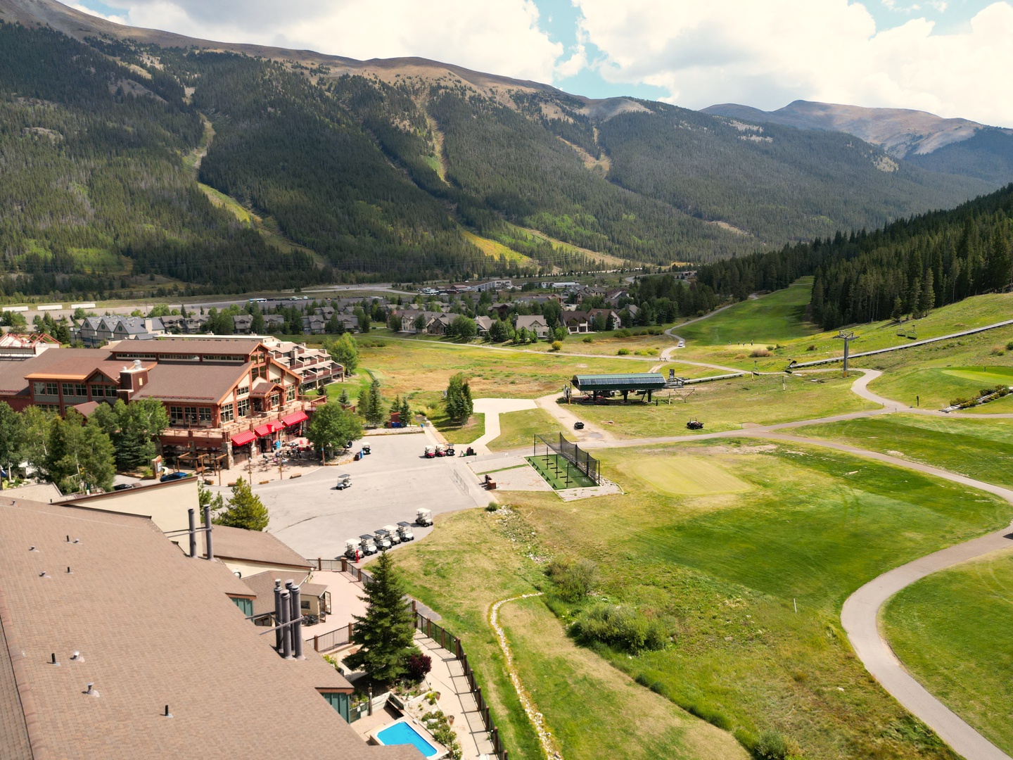 Mountain resort village nestled in a spectacular alpine valley with ski slopes and forested peaks surrounding the area.