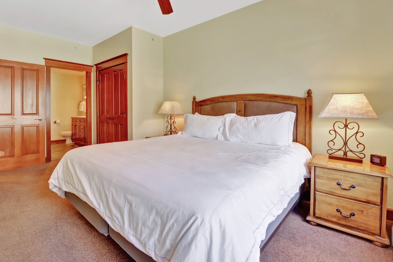 Sink into crisp, white linens on your plush bed—matching nightstands and warm wood finishes create a cozy retreat. Plenty of storage awaits in your wardrobe for settling in.