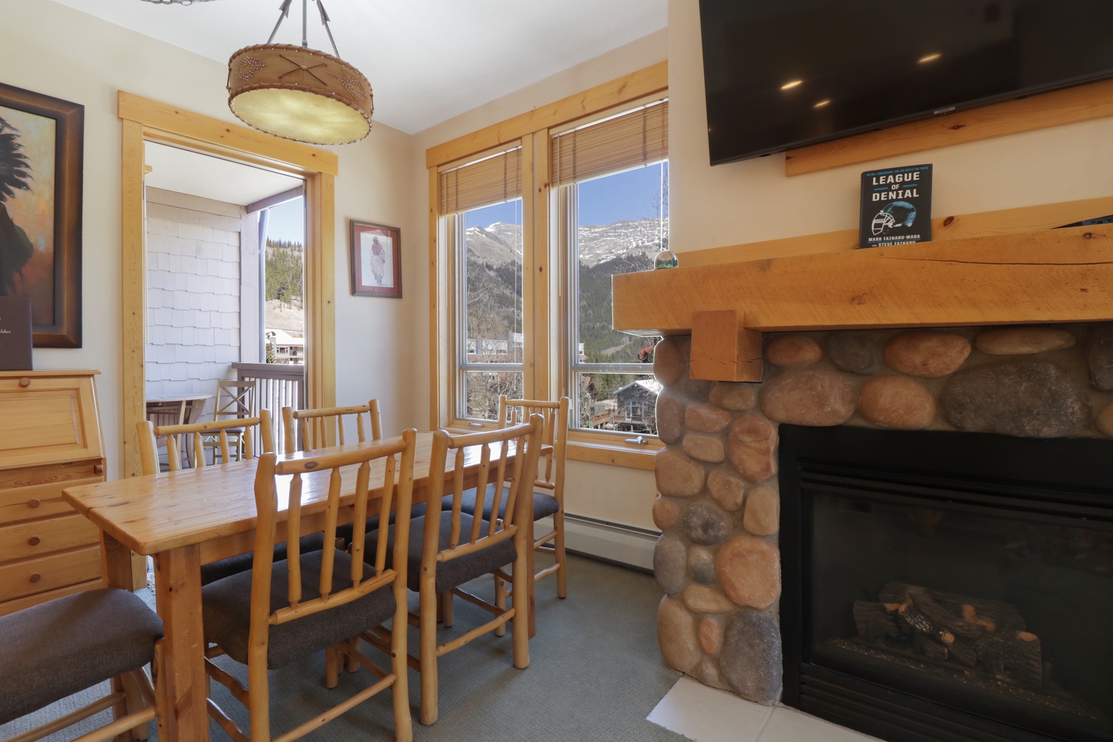 Gather around your dining table with mountain views through large windows, while the stone fireplace creates warmth for memorable meals together.