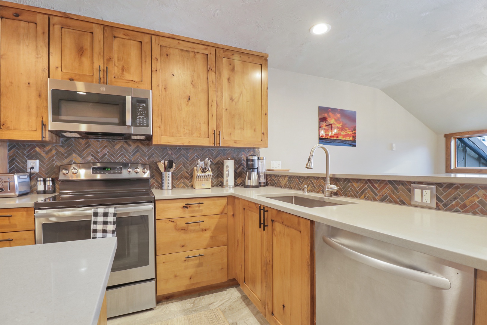 Step into your fully equipped mountain kitchen where warm wood cabinets and modern stainless steel appliances create the perfect blend of rustic charm and contemporary convenience for your stay.