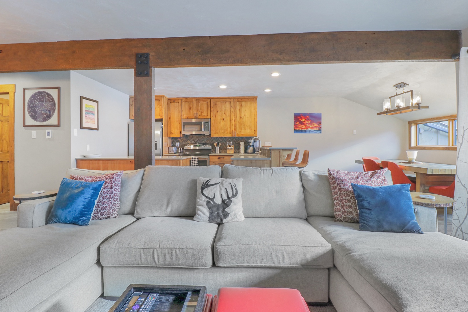Settle into your cozy open-concept living space where rustic wooden beams meet modern comfort. Sink into the plush sectional sofa with colorful pillows while you plan mountain adventures or simply relax after a day exploring.