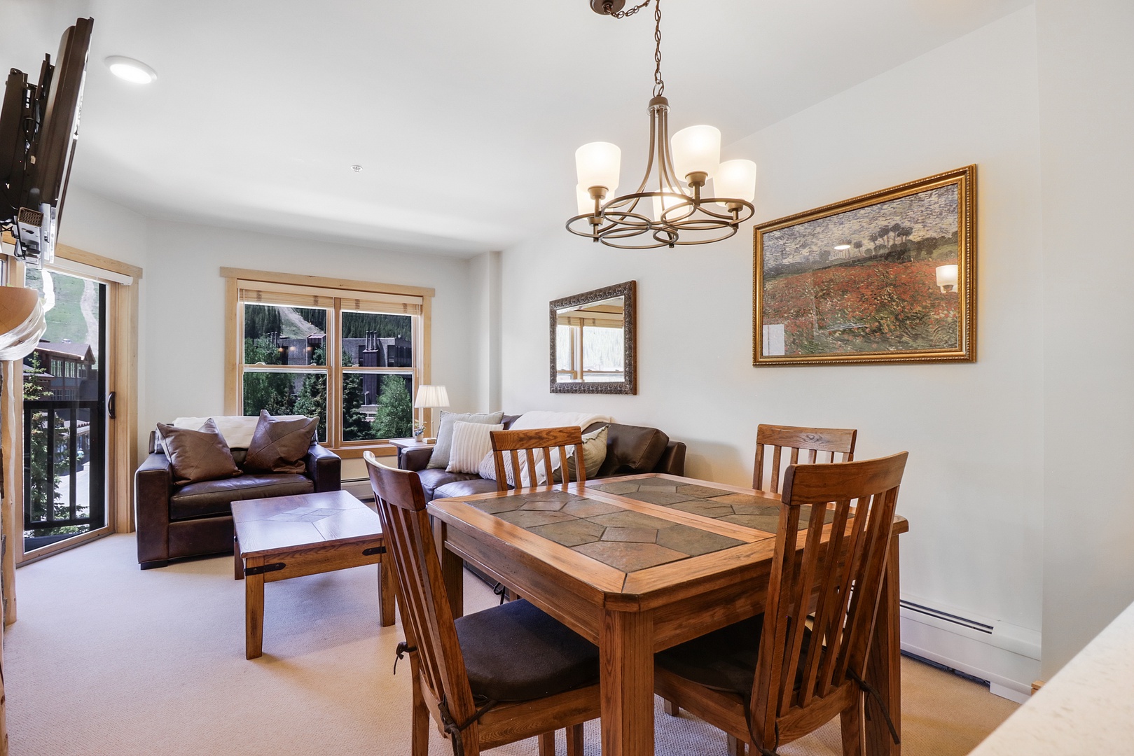 Unwind in your open-concept living and dining area, where warm wood accents, a cozy leather sofa, and mountain-view windows create the perfect space to relax and share meals together.