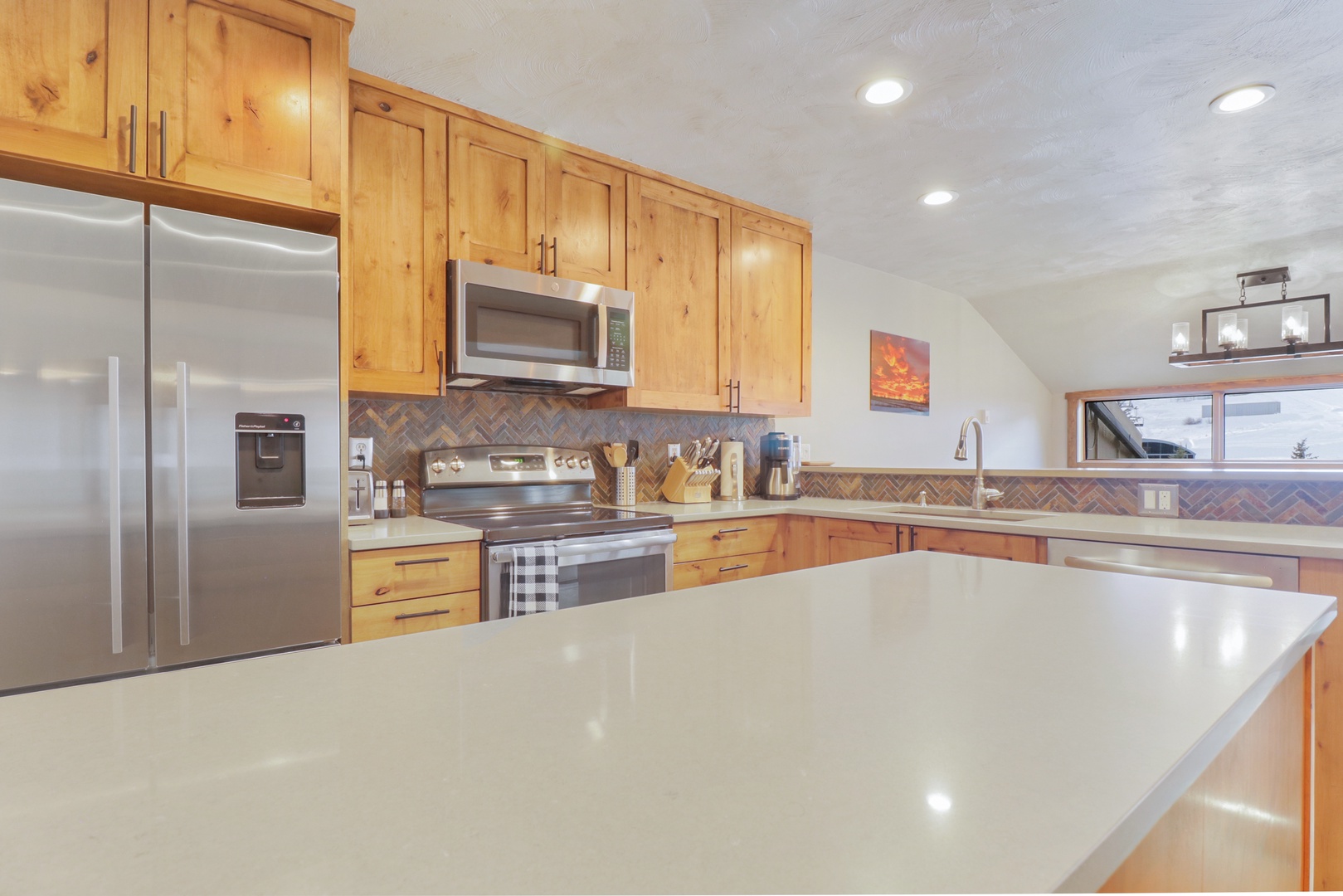 Your fully-equipped kitchen awaits with warm wood cabinetry, gleaming countertops, and stainless steel appliances - perfect for preparing memorable meals together.