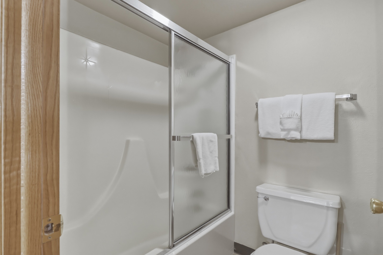 Step into your private bathroom featuring a spacious shower with gleaming glass doors and fresh towels awaiting your arrival.