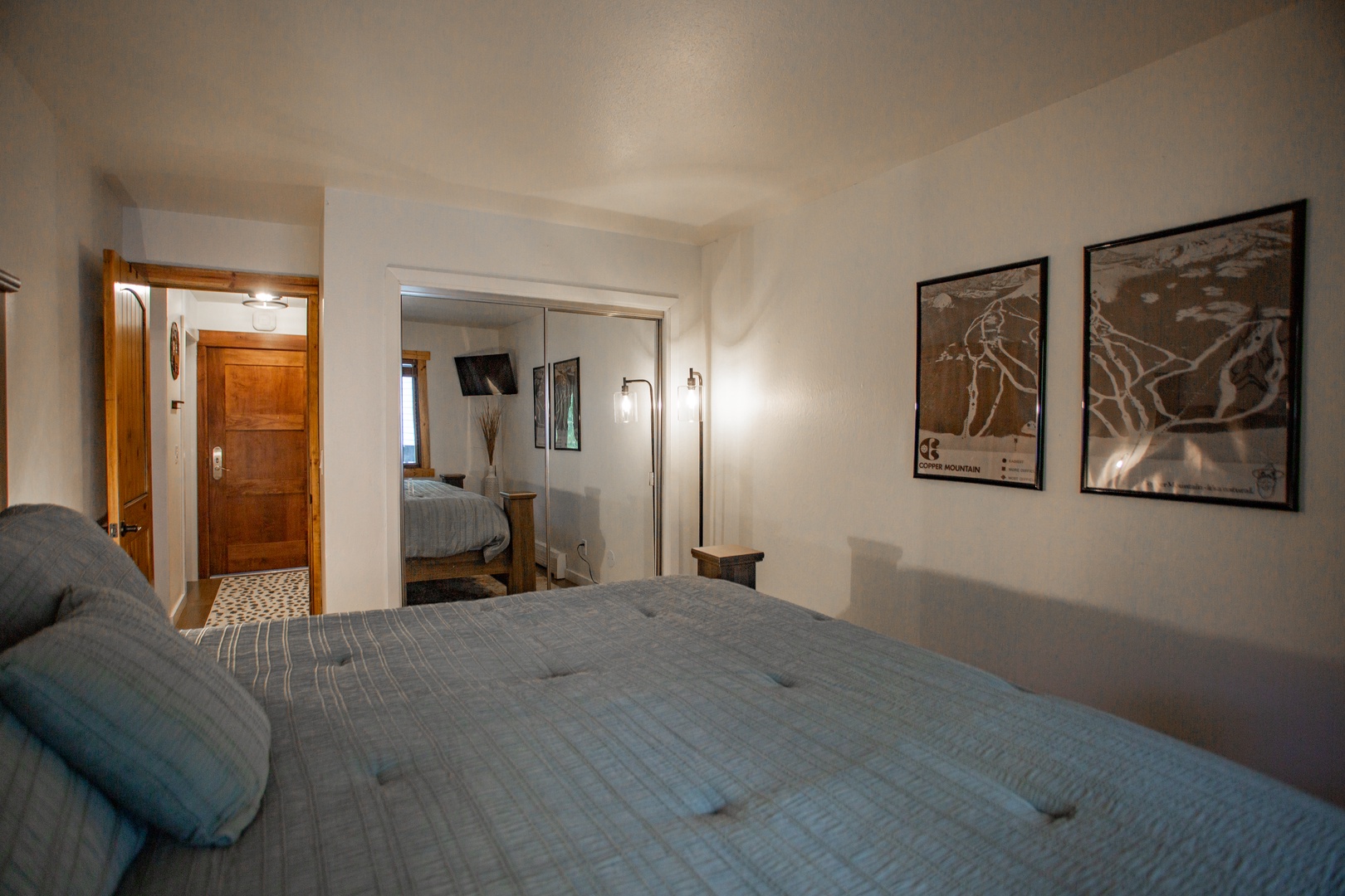 Your serene bedroom features a plush bed and mirrored closet doors that reflect the soft lighting throughout the space. Relax in this peaceful retreat after a day of adventure.