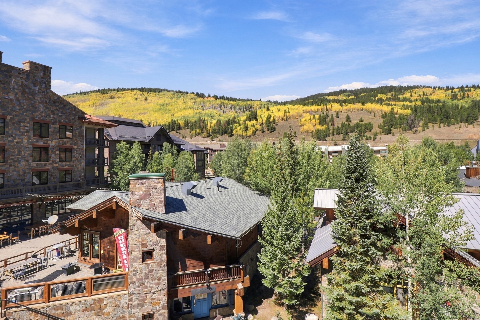 A mountain resort community nestled among evergreens, with golden aspens blanketing the hillsides in autumn splendor.