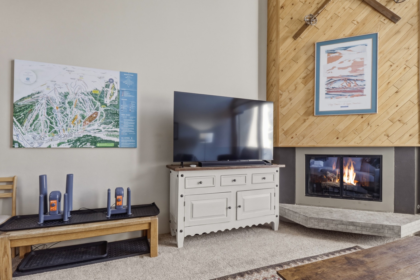 Cozy up in your living room with a crackling fireplace, entertainment center, and mountain maps inspiring your next adventure.