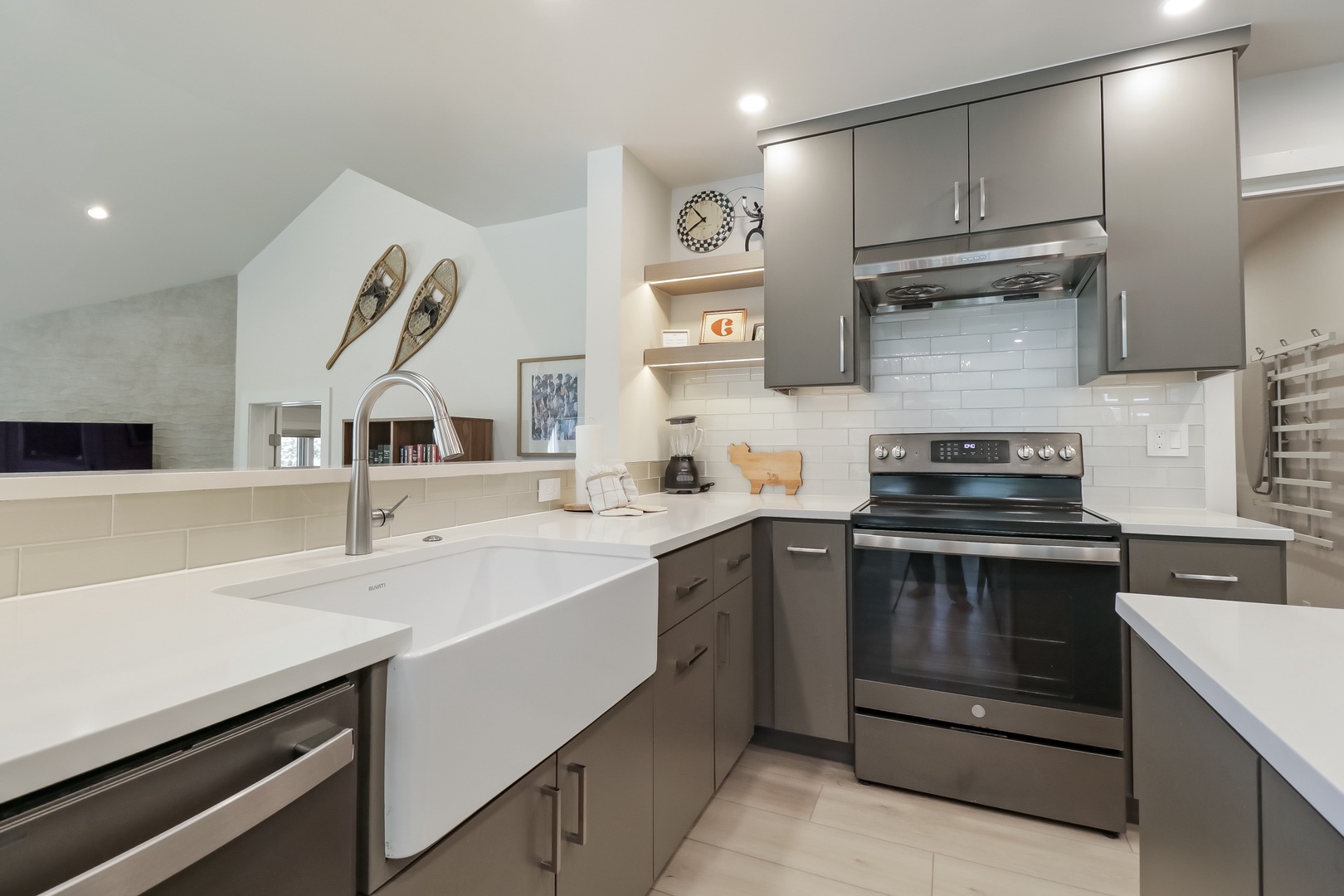 Your modern kitchen awaits, with sleek grey cabinetry, white quartz counters, and stainless steel appliances ready for your culinary adventures. Enjoy the stylish white subway tile backsplash and thoughtful touches like the farmhouse sink.