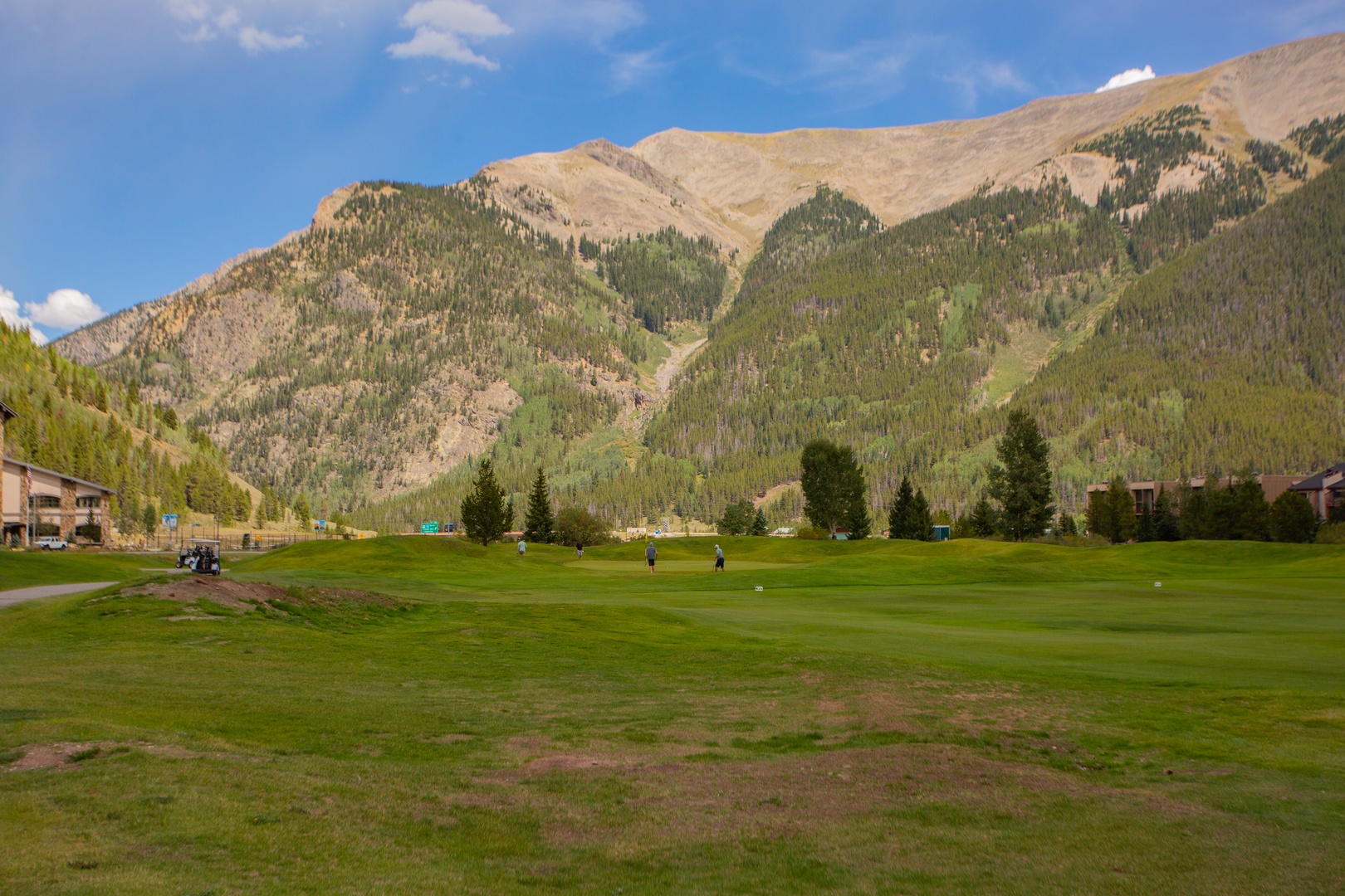 A picturesque golf course that is set against a stunning mountain backdrop, offering recreation amid natural alpine beauty and forested slopes.