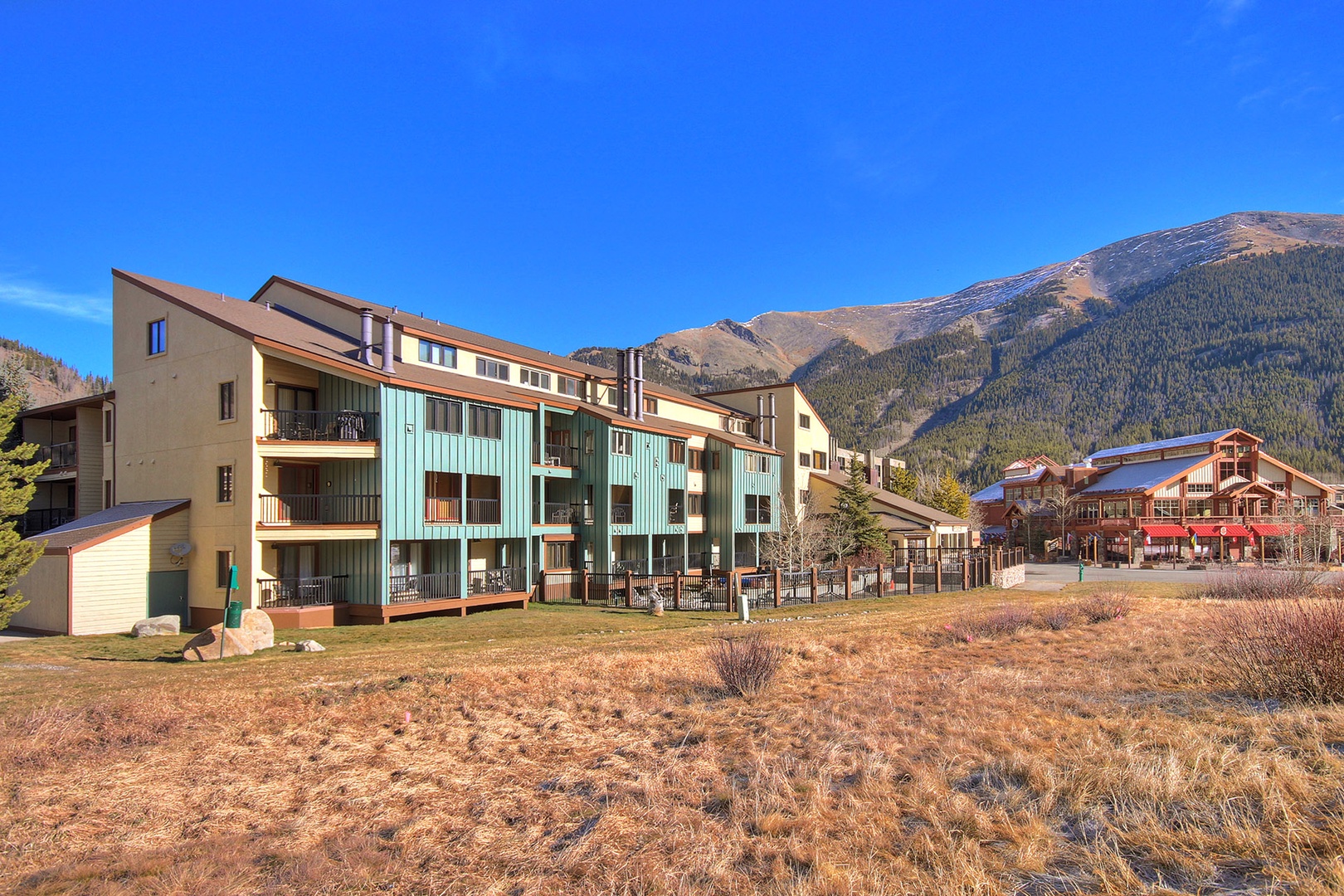 Mountain resort buildings nestled against dramatic peaks, offering proximity to village amenities and stunning alpine scenery.