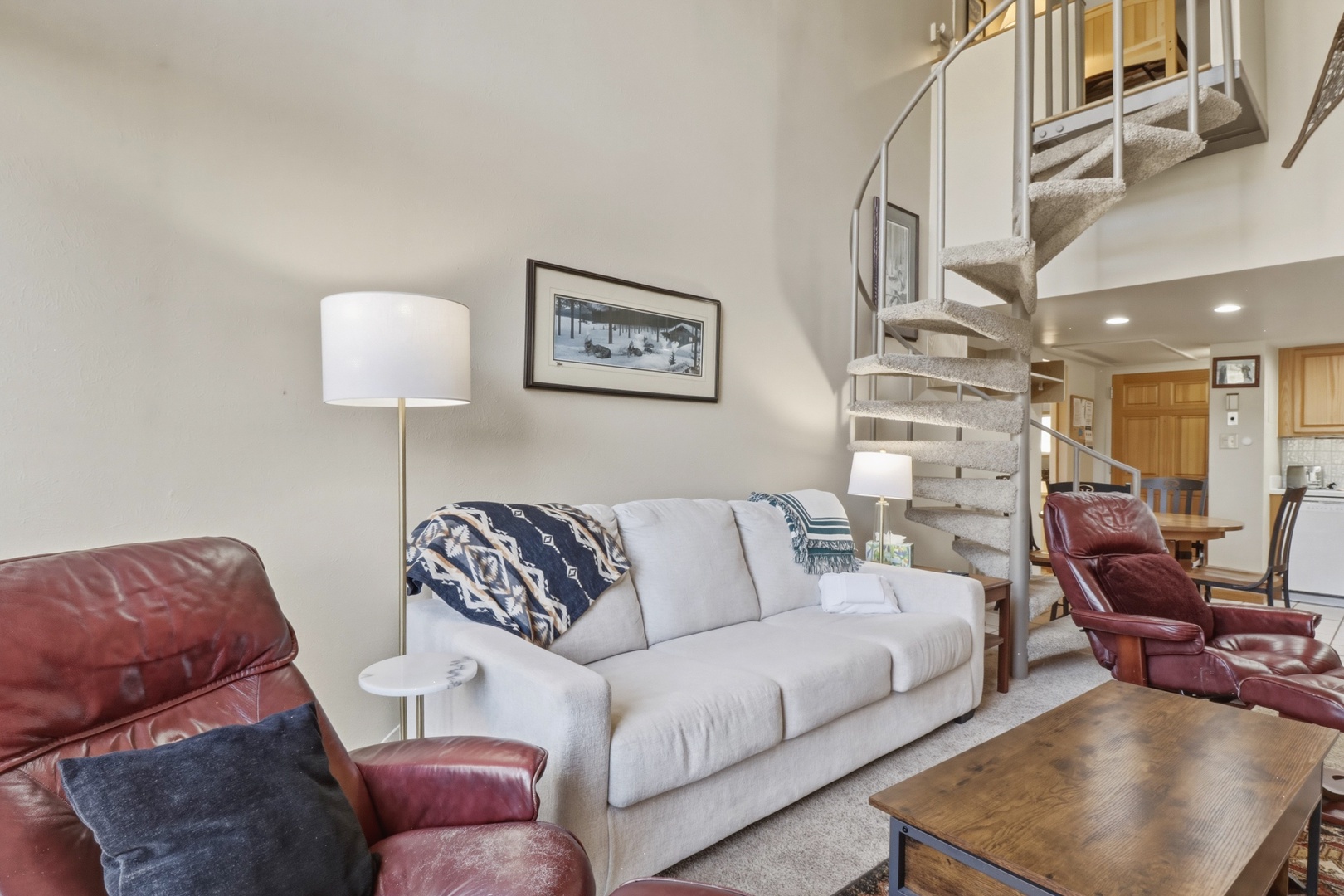 Relax in your cozy living room with plush seating and warm lighting, while the elegant spiral staircase leads to your private upstairs retreat.