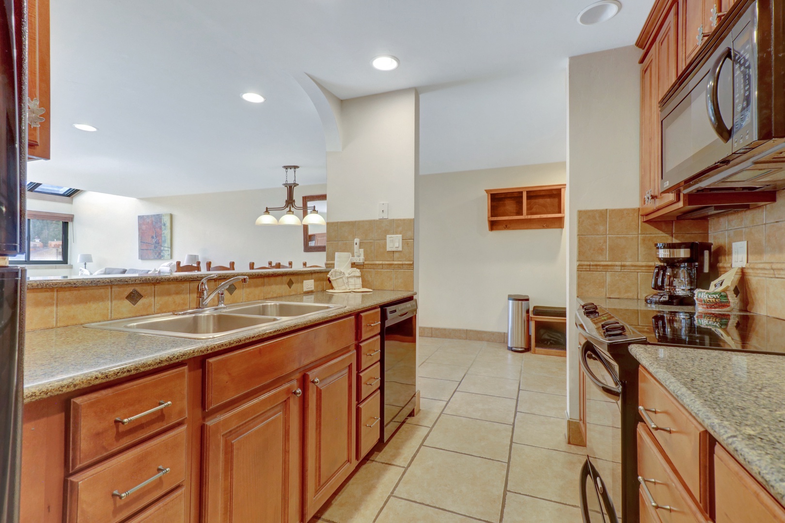 Well-equipped kitchen featuring granite countertops, stainless steel appliances, and warm wood cabinetry. Perfect for preparing meals after a day of mountain adventure.