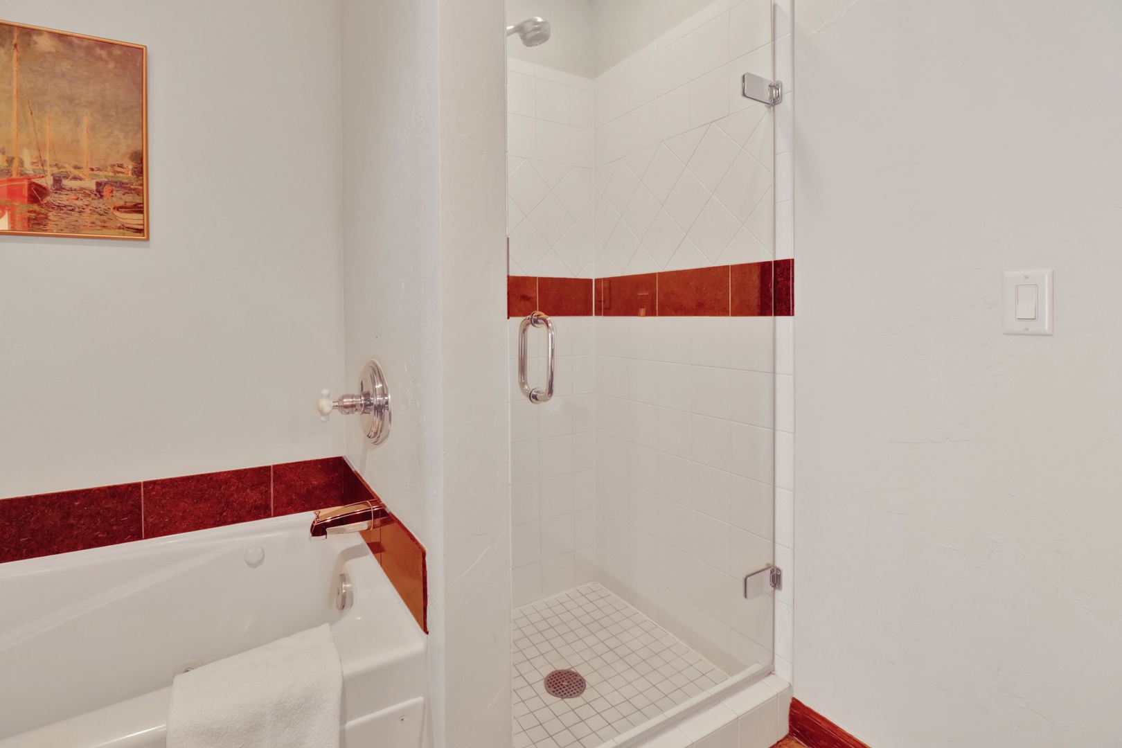 Refresh and unwind in your modern bathroom, featuring a full tub and spacious walk-in shower with elegant tile accents that add a touch of warmth to the crisp, clean design.