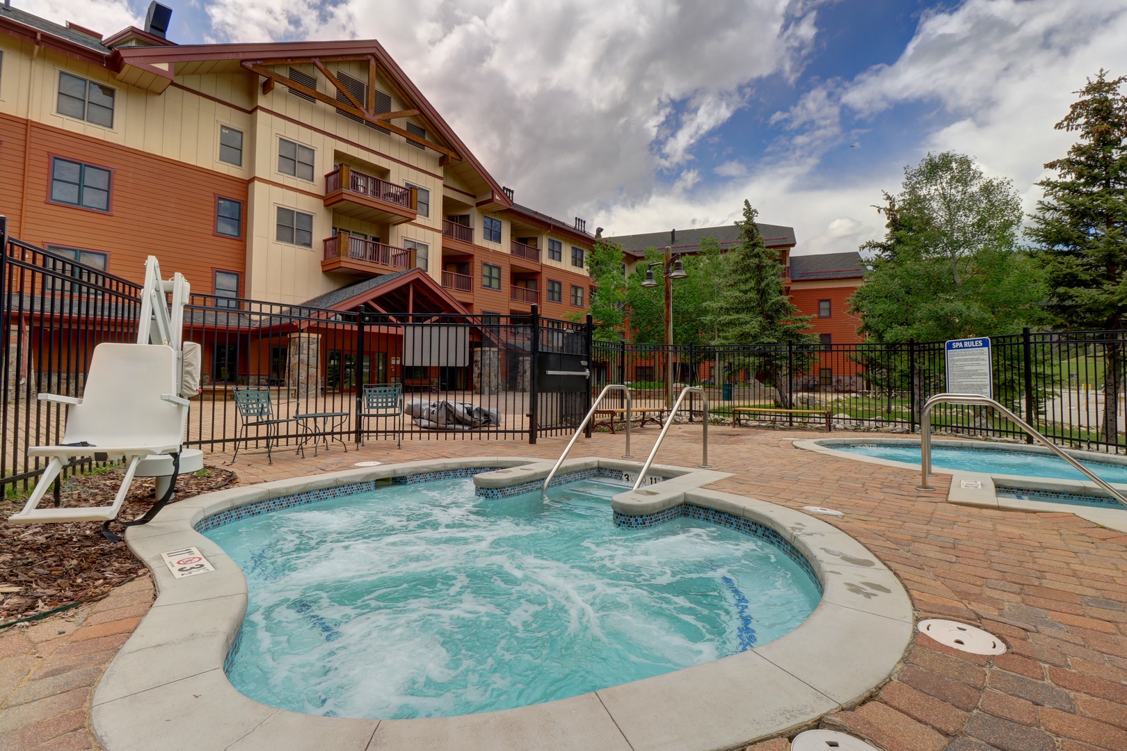 Multiple outdoor hot tubs await with mountain lodge-style architecture surrounding this spacious patio area, ideal for unwinding after exploring the nearby trails and attractions.